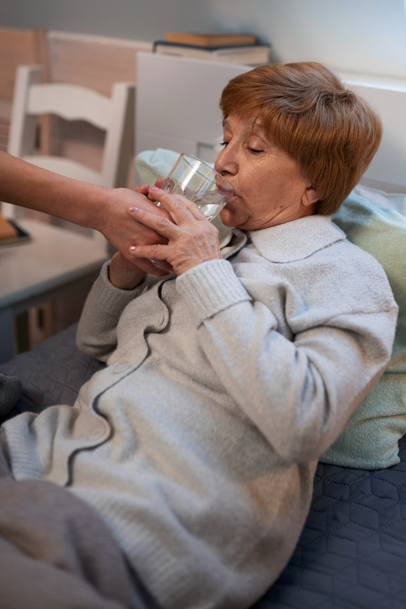 Una mujer ayudando a beber agua a una mujer de mediana edad enferma | Fuente: Freepik