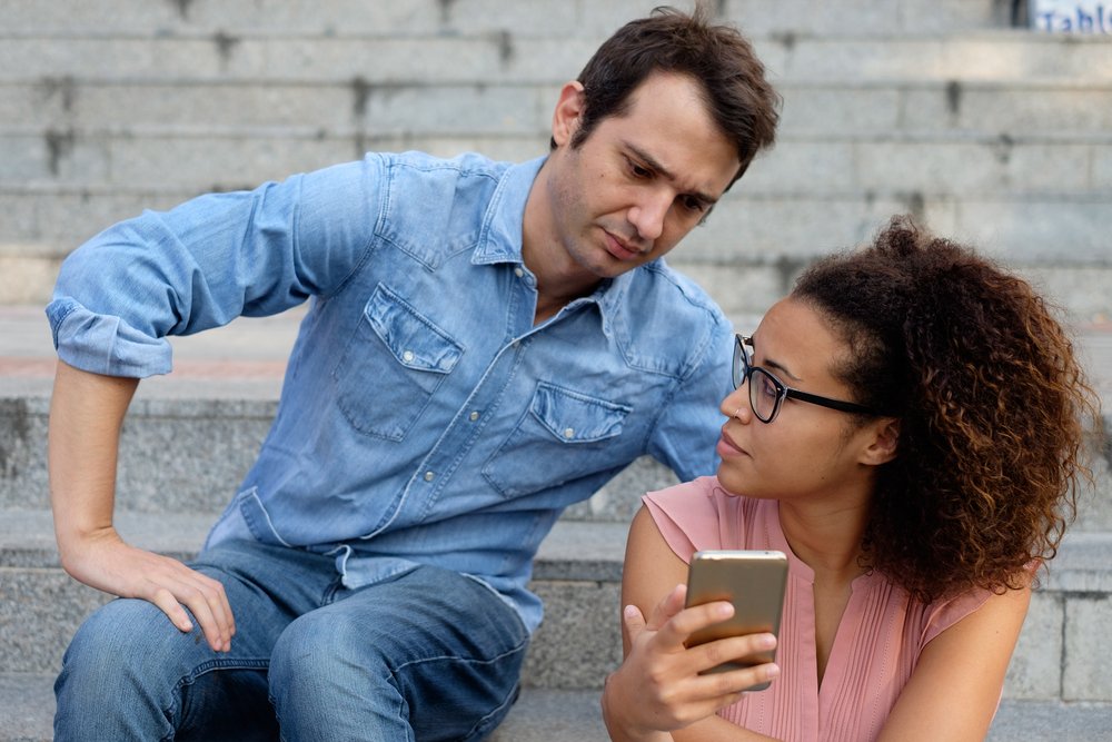 Hombre queriendo ver qué hace su novia con su celular. | Foto: Shutterstock.