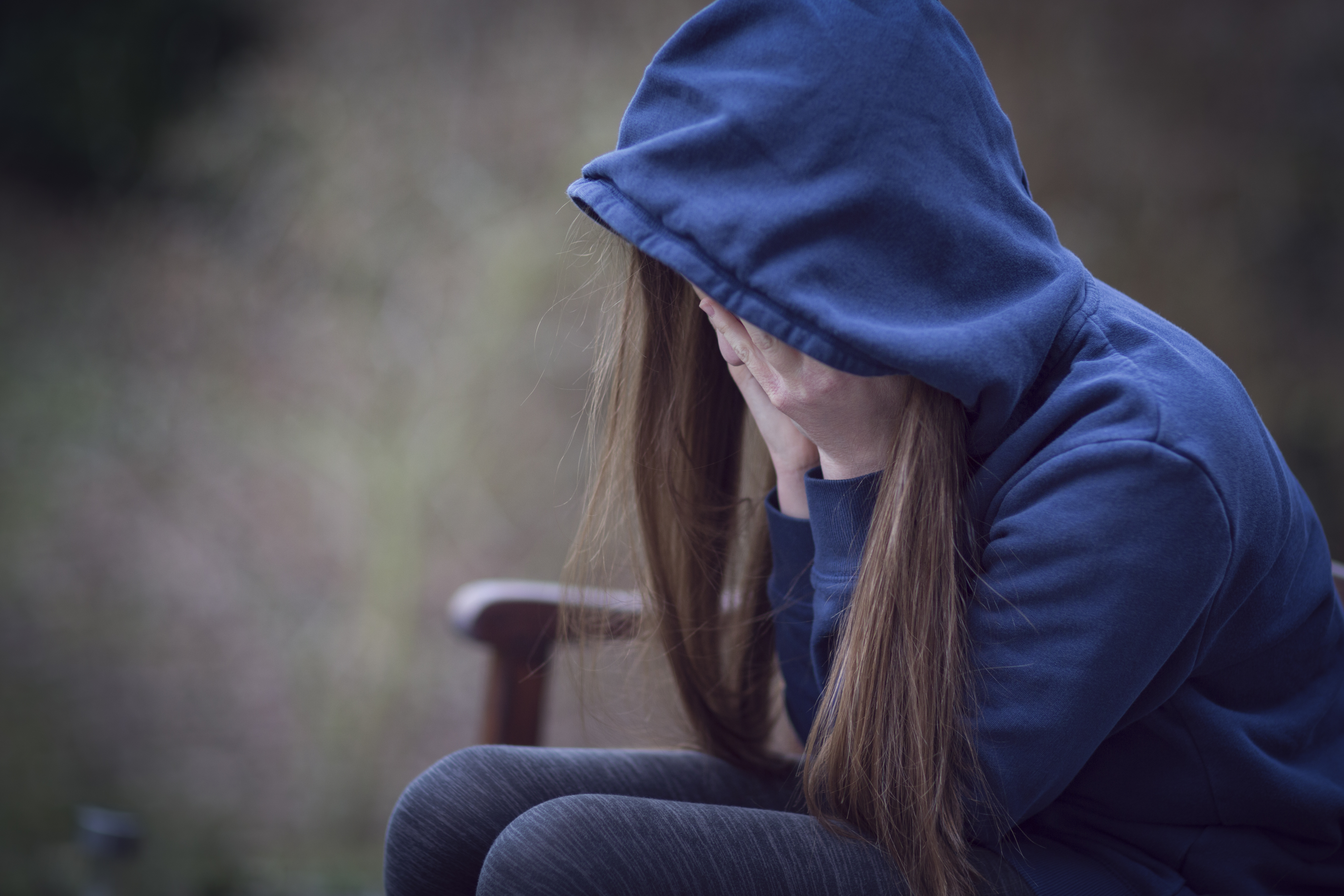 Adolescente con capucha y la cabeza entre las manos, desesperada | Foto: Getty Images