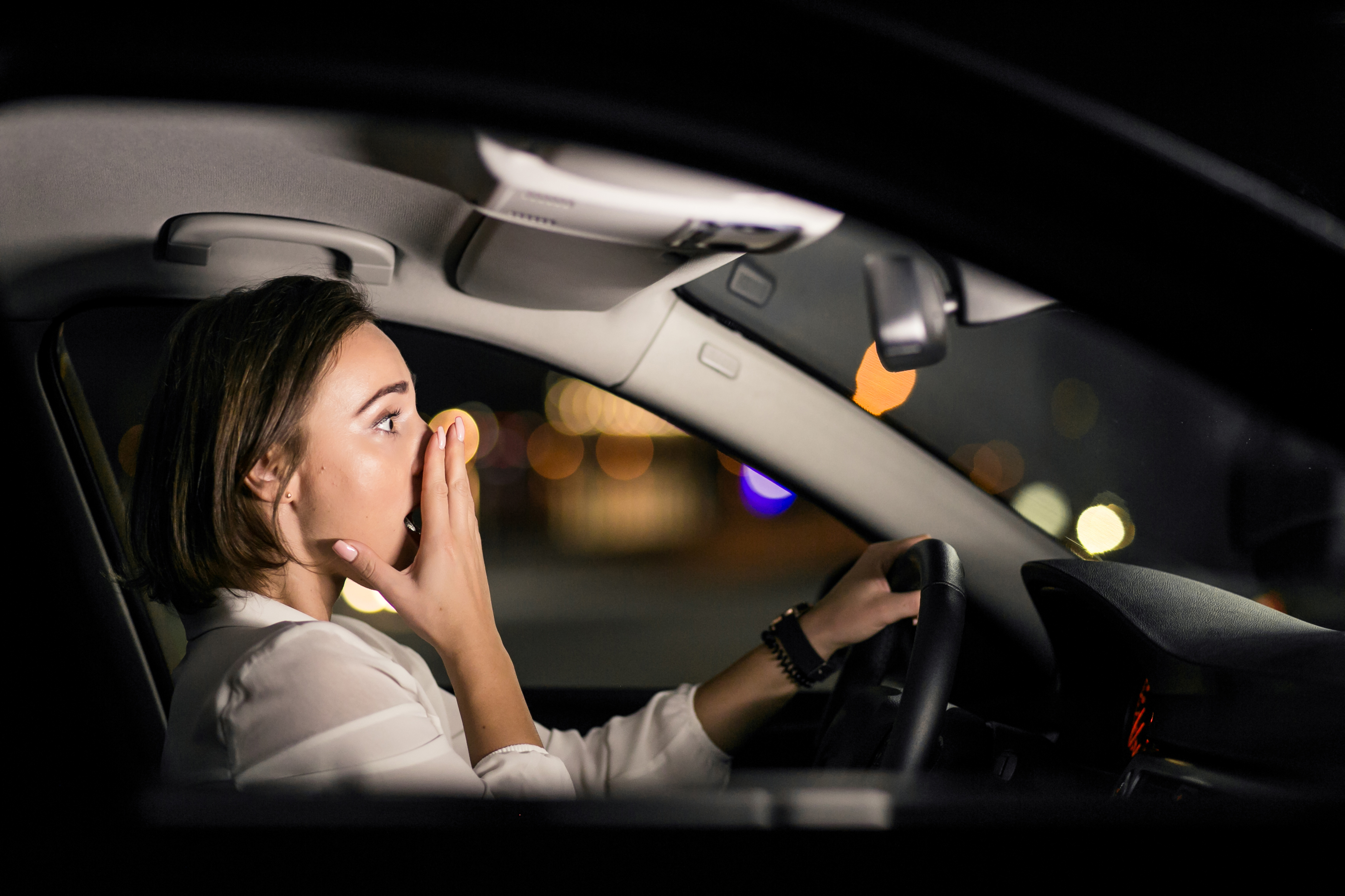 Foto nocturna de una mujer conmocionada conduciendo un Automóvil | Fuente: Freepik