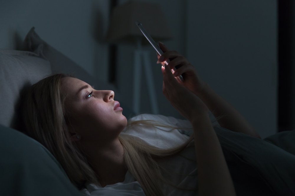 Mujer revisando su celular en horas de la noche. | Foto: Shutterstock