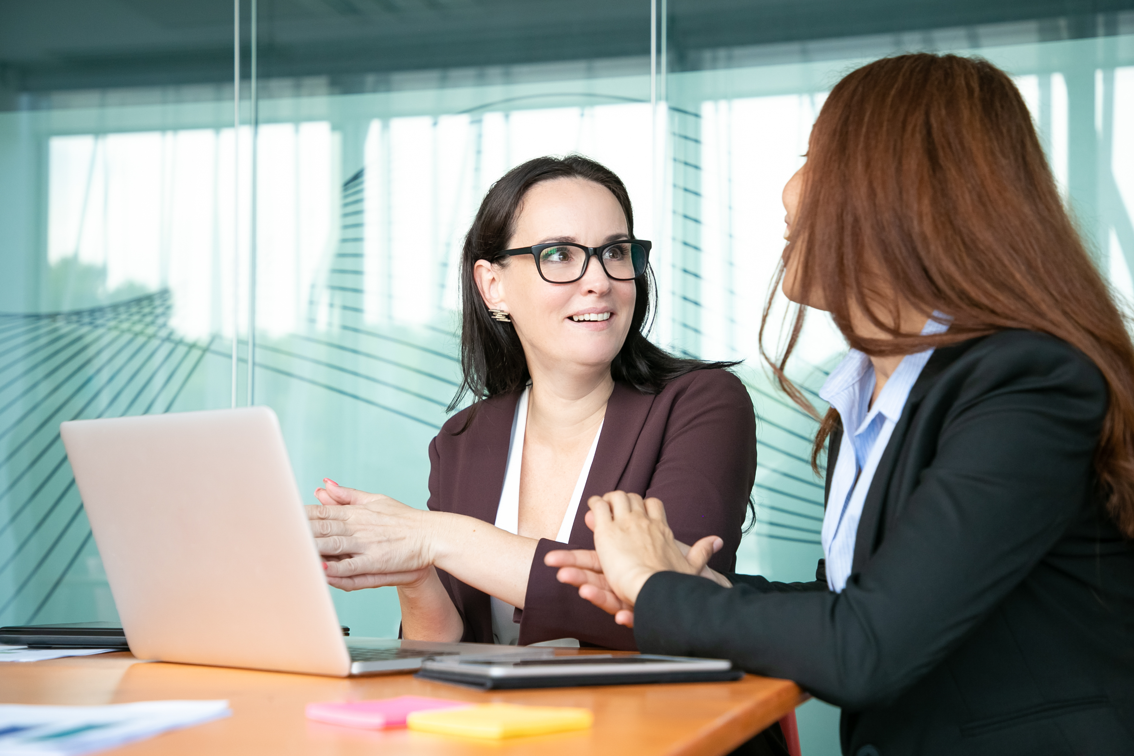 Una mujer sonriente charlando con su compañero de trabajo | Fuente: Freepik