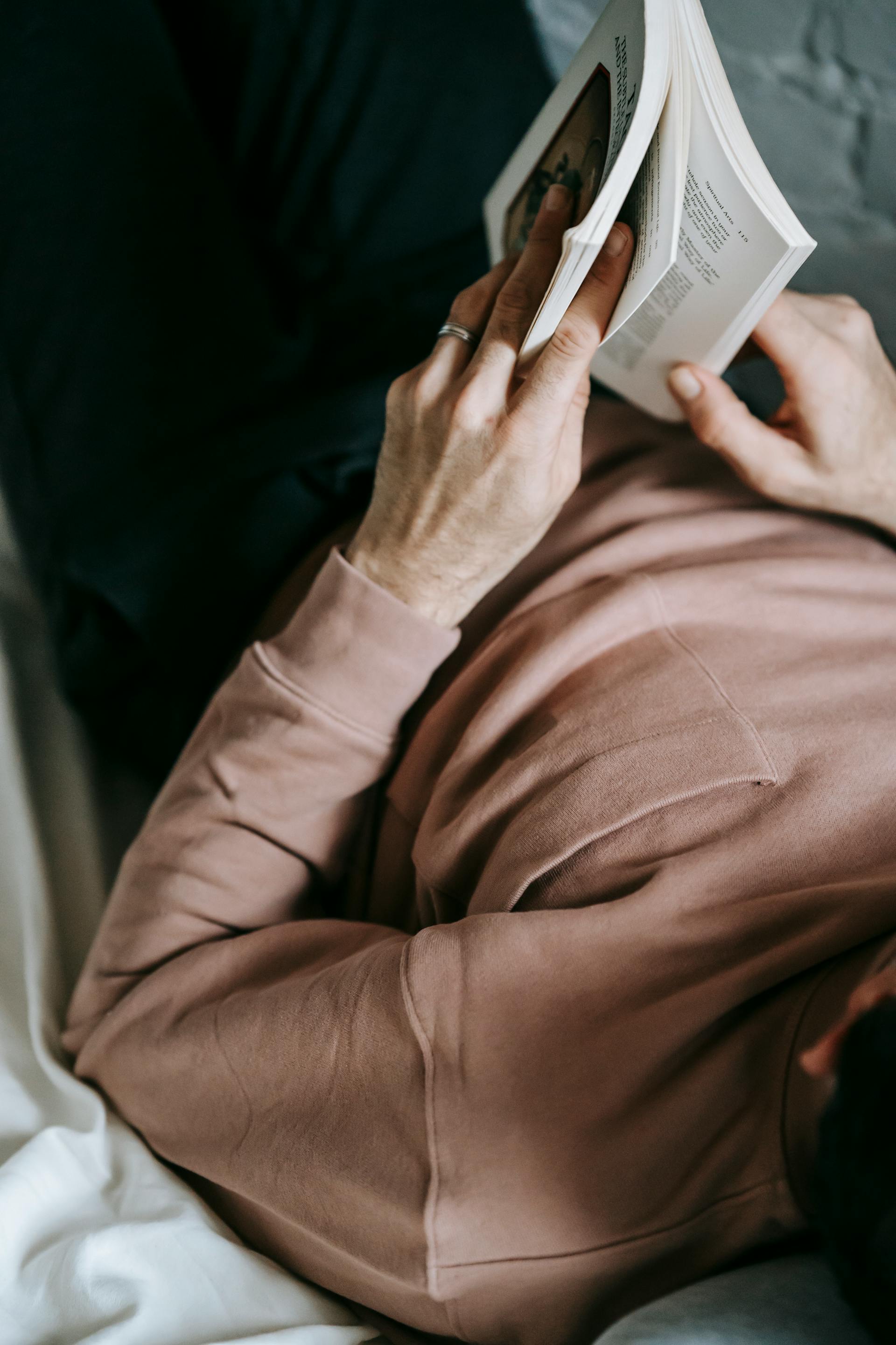 Primer plano de un hombre leyendo un libro en la cama | Fuente: Pexels