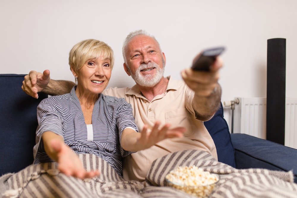 Hombre mira TV junto a esposa exasperada. Fuente: Shutterstock