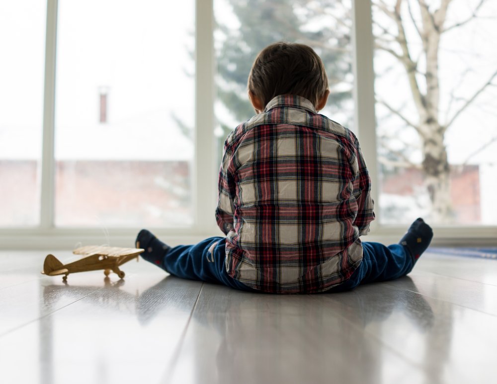 Niño sentado en el suelo frente a un ventanal. | Foto: Shutterstock