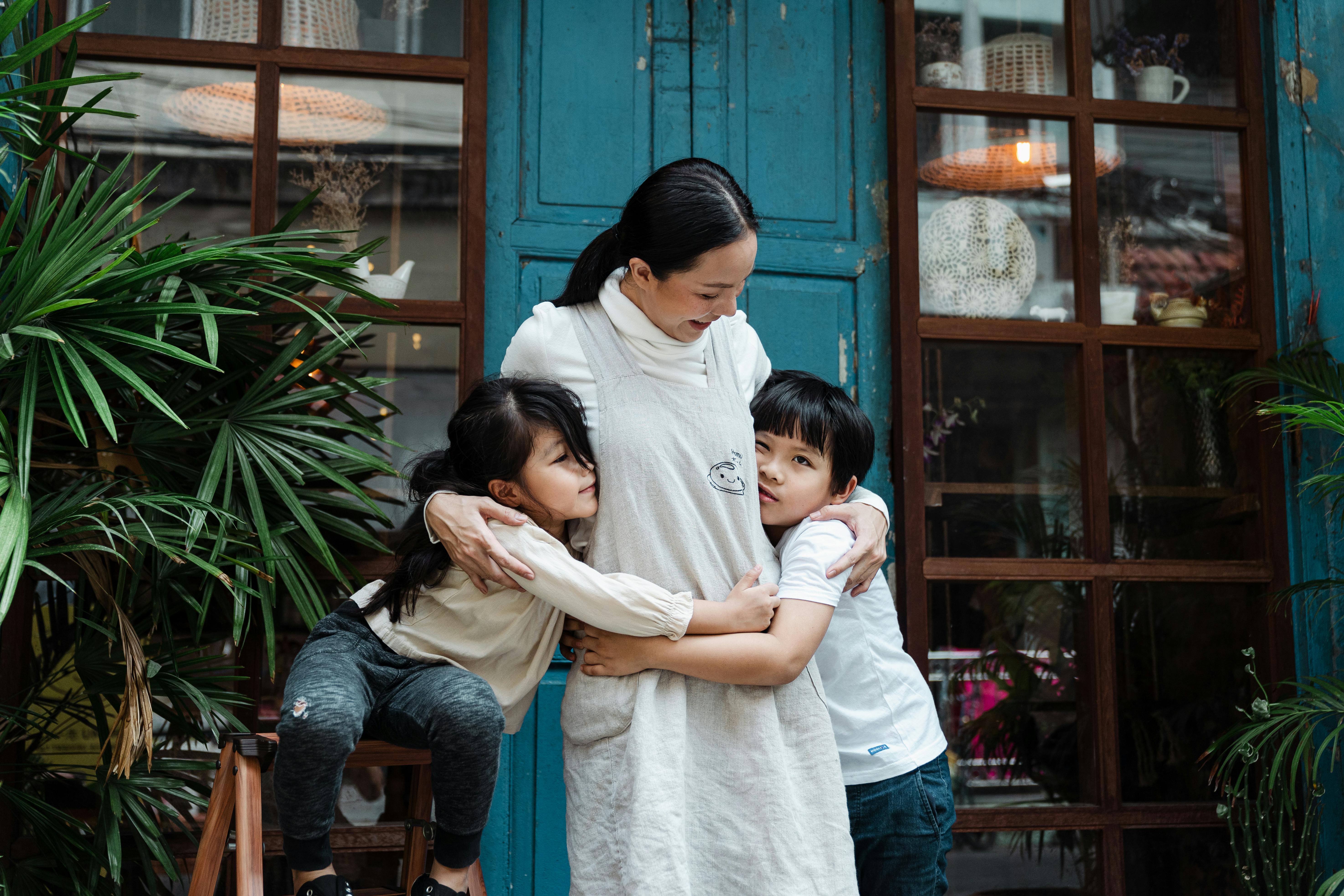 Una mujer abraza a dos niños pequeños | Foto: Pexels