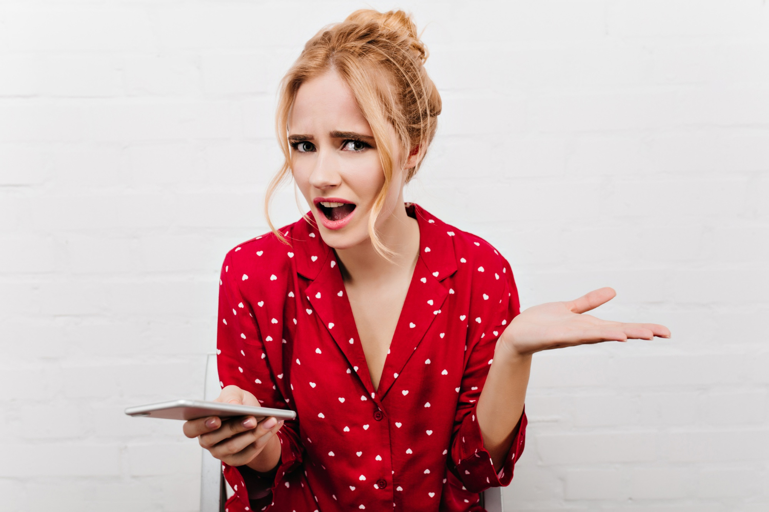 Una mujer confundida sujetando su teléfono | Fuente: Freepik