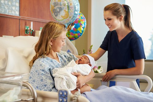 Enfermera entrega al bebé a su madre después del parto en el hospital. | Foto: Shutterstock