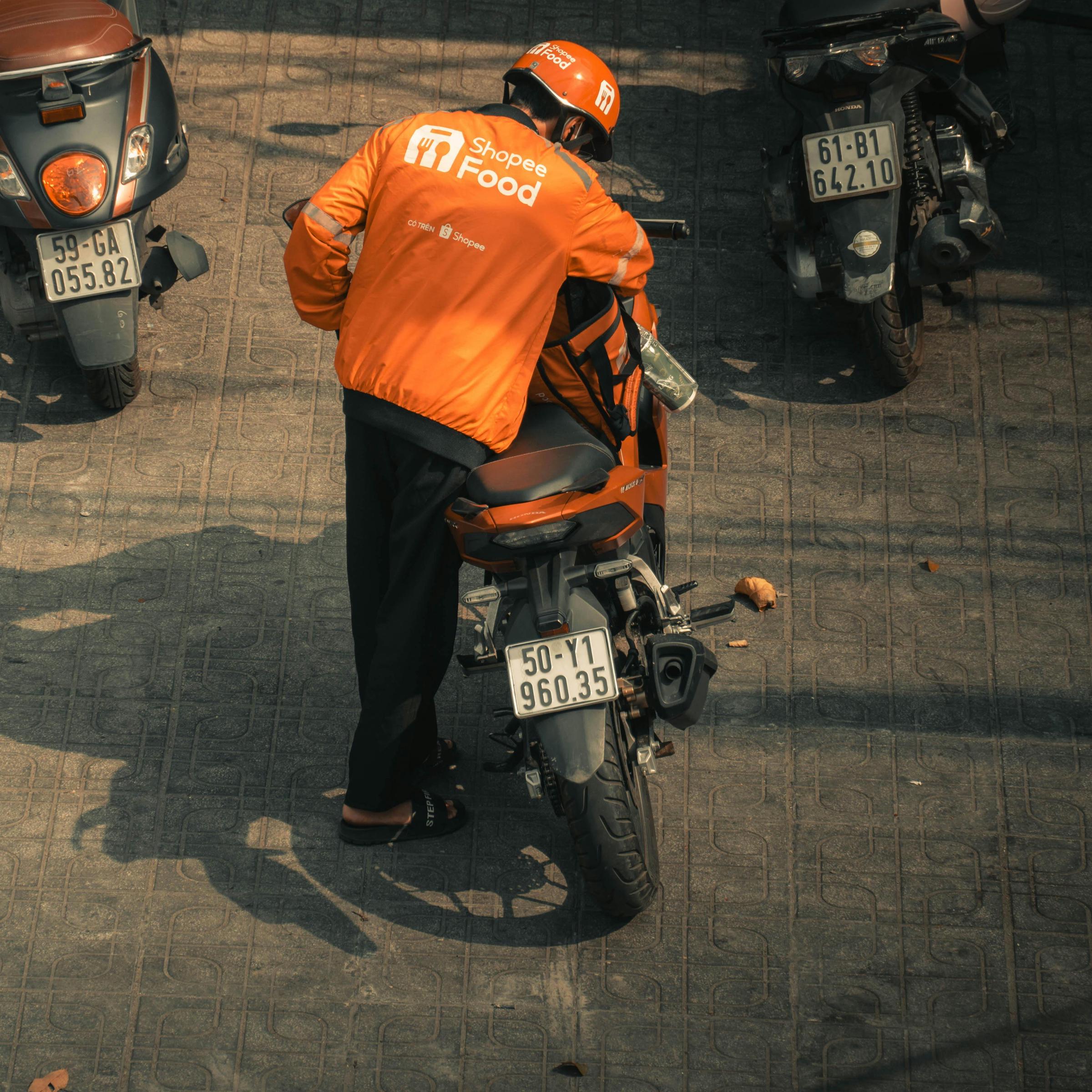 Un repartidor de comida ensillando su moto | Fuente: Pexels