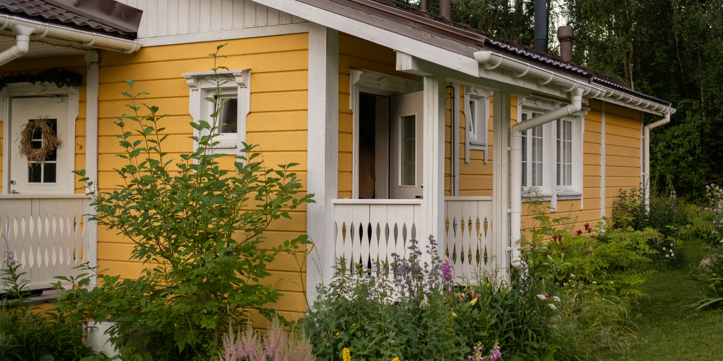 Una casita amarilla rodeada de vegetación | Fuente: Pexels
