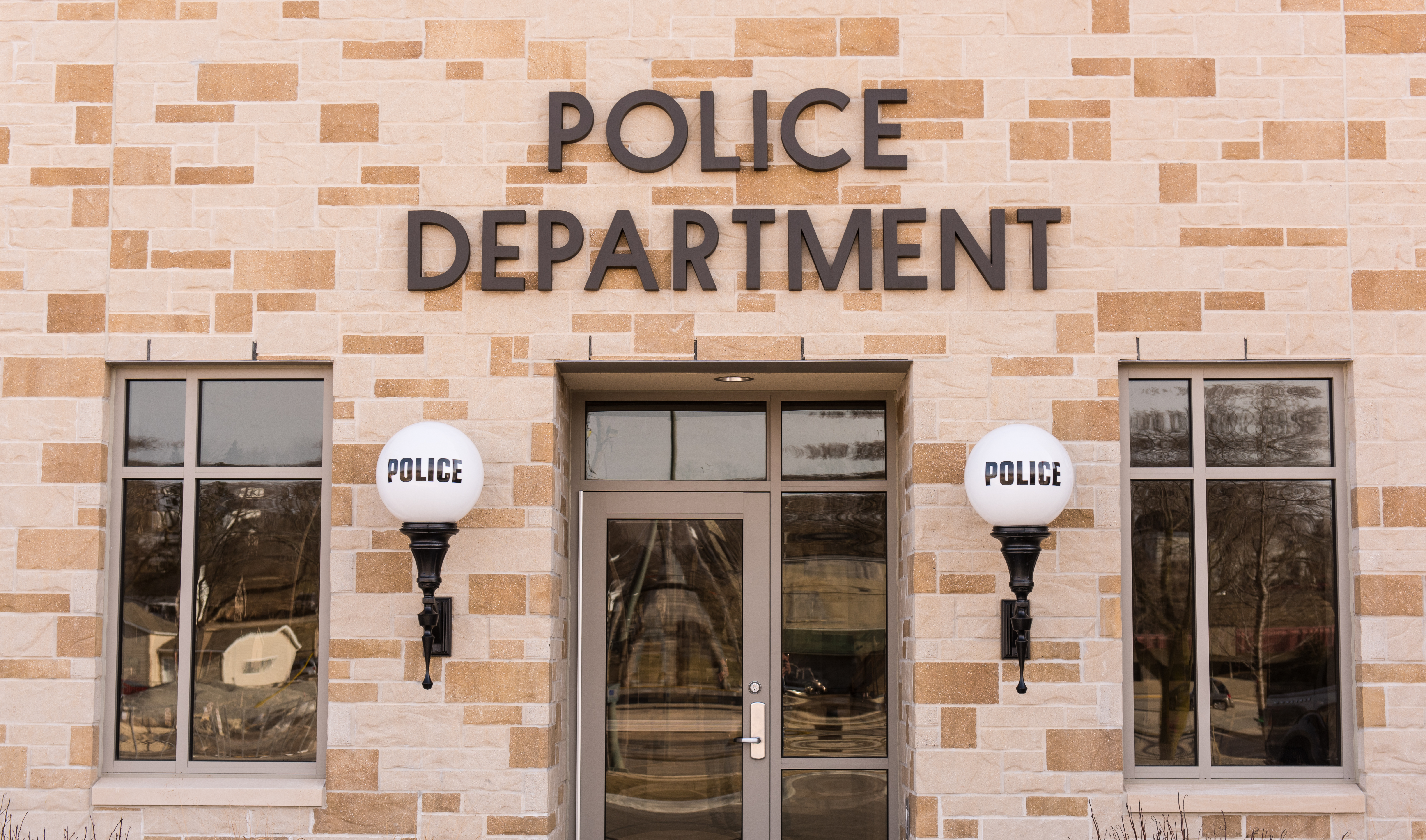 Toma de una comisaría de policía con luces a ambos lados de la puerta que dicen policía en ellas. | Fuente: Shutterstock