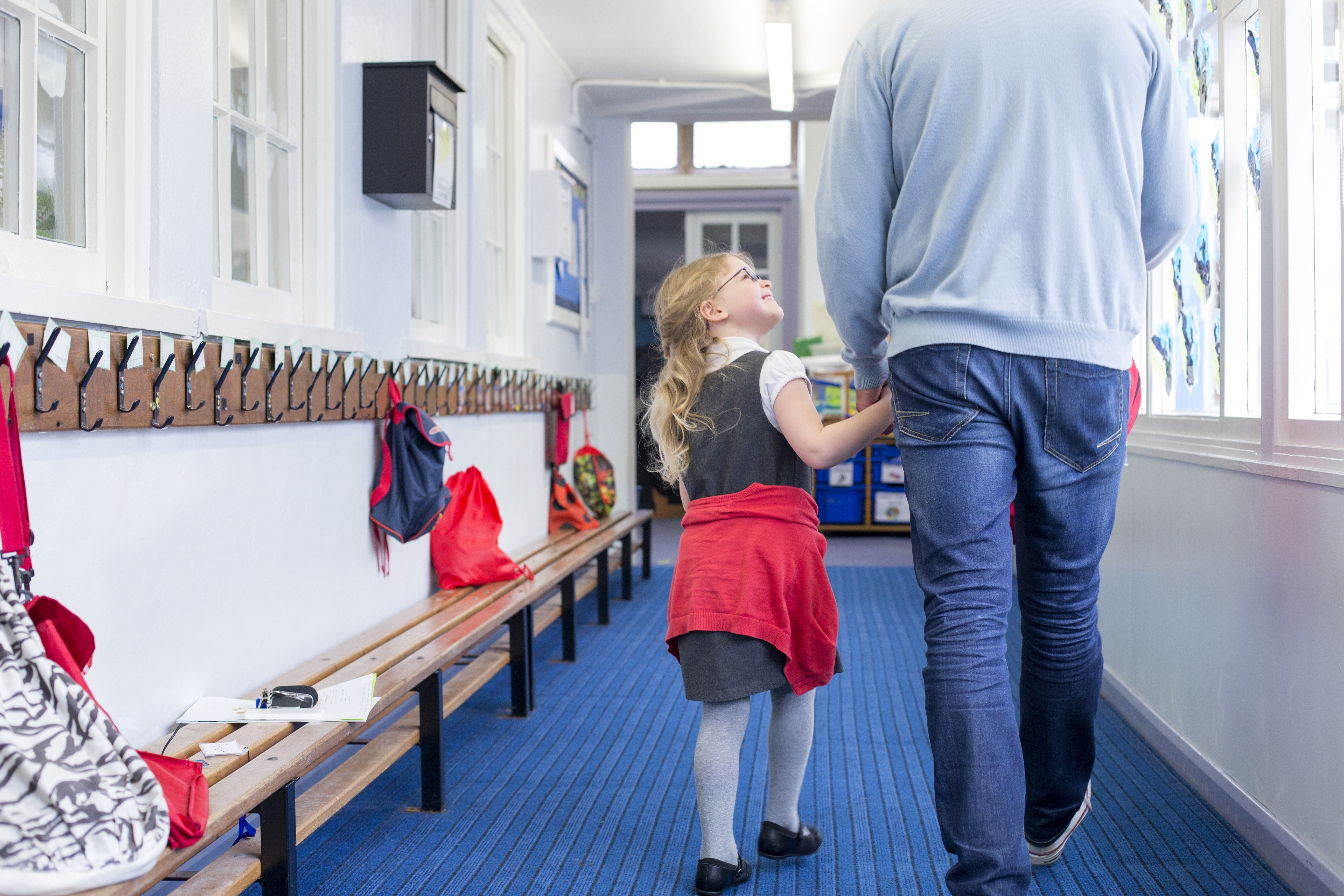 Niña sonriendo y cogida de la mano de un hombre mientras caminan por un pasillo | Foto: Shutterstock