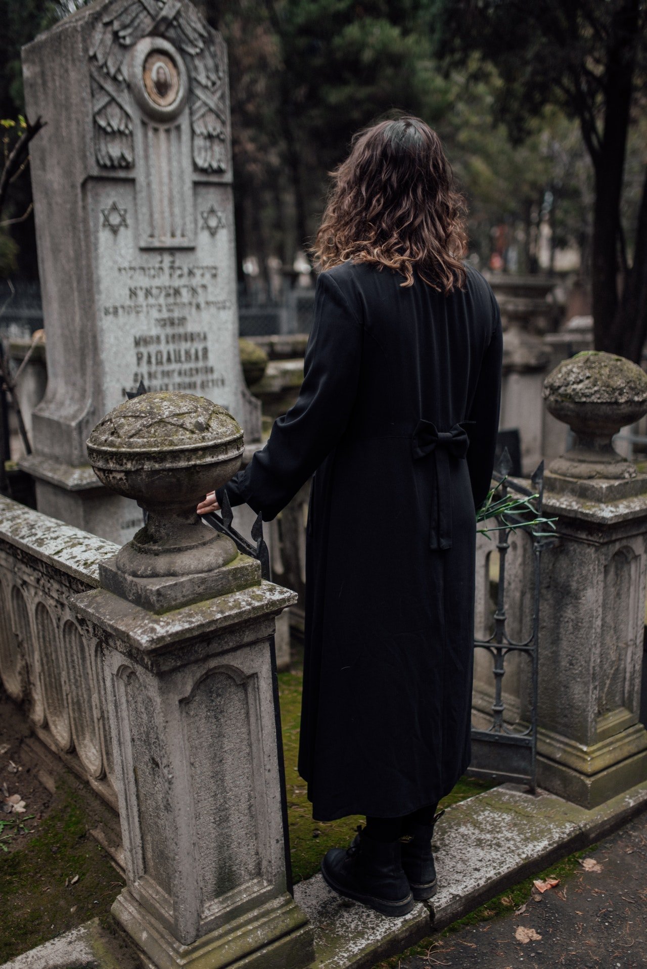 Mujer frente a una tumba en un cementerio. | Foto: Pexels