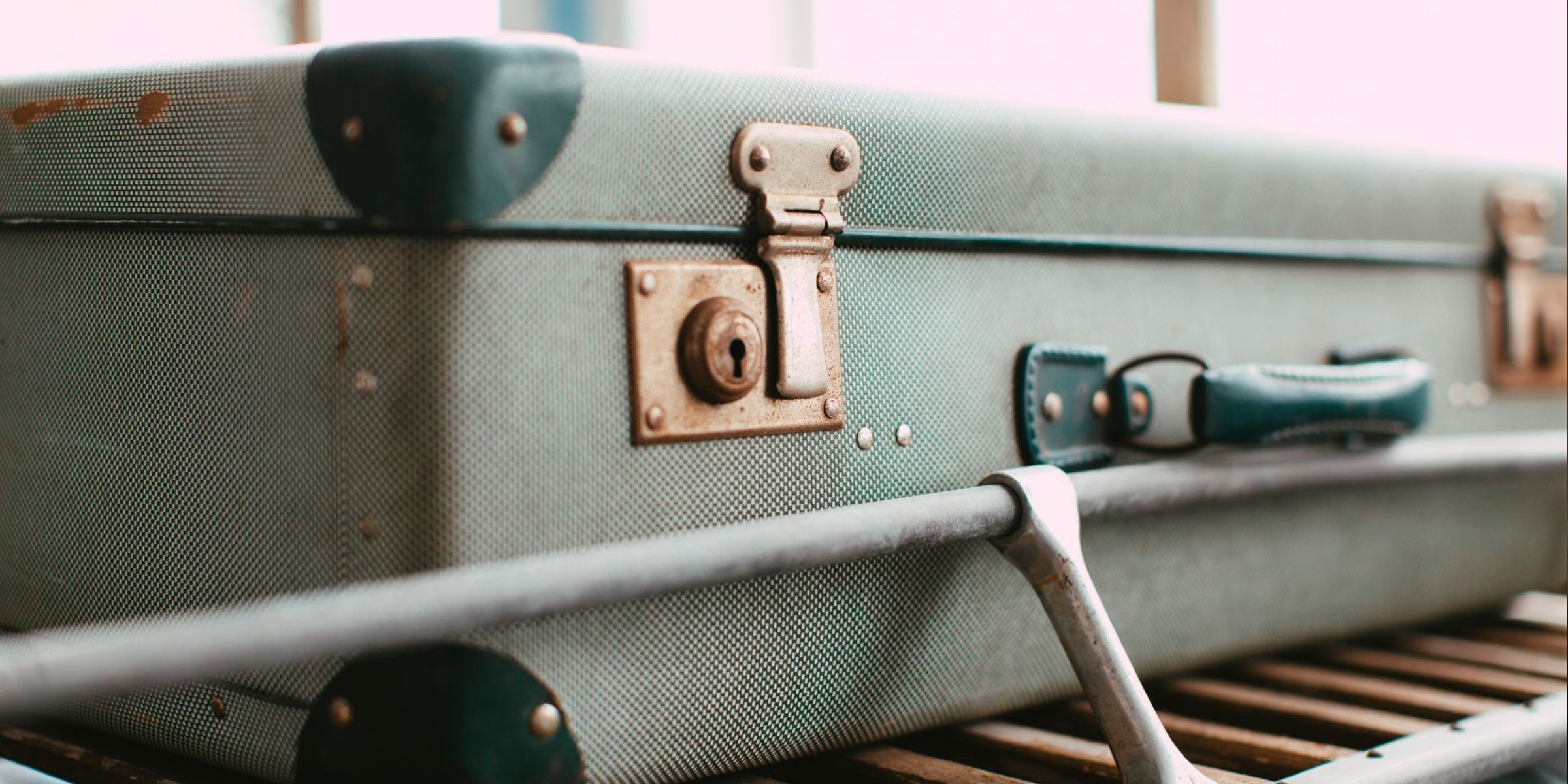 Primo piano di una valigia vintage verde con finiture in metallo, che trasmette un'atmosfera da viaggio retrò | Fonte: Pexels