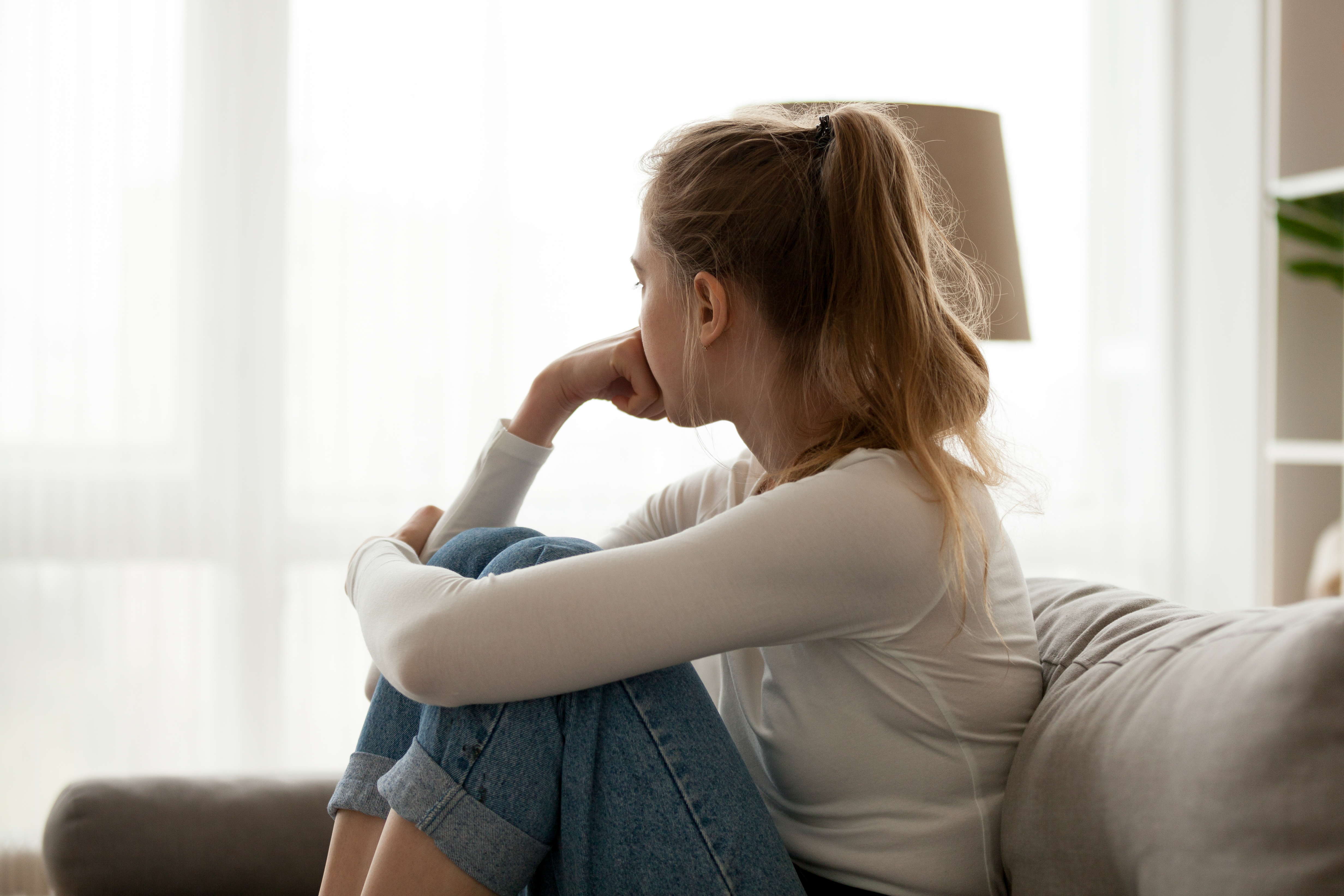 Foto de una mujer sumida en profundos pensamientos mientras está sentada en un sofá. | Foto: Shutterstock