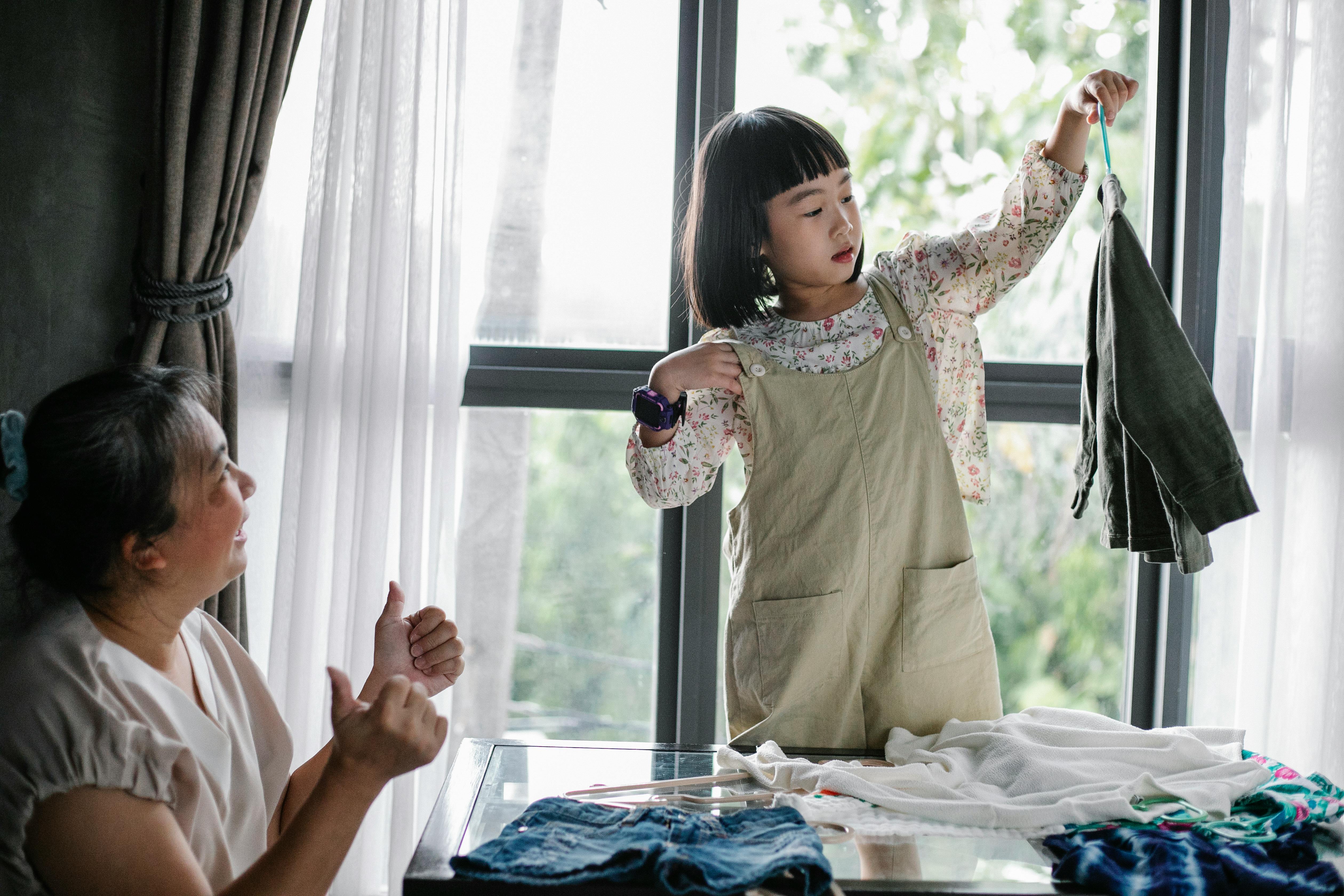 La madre de una niña orgullosa de ella por ser capaz de colgar su propia ropa | Fuente: Pexels