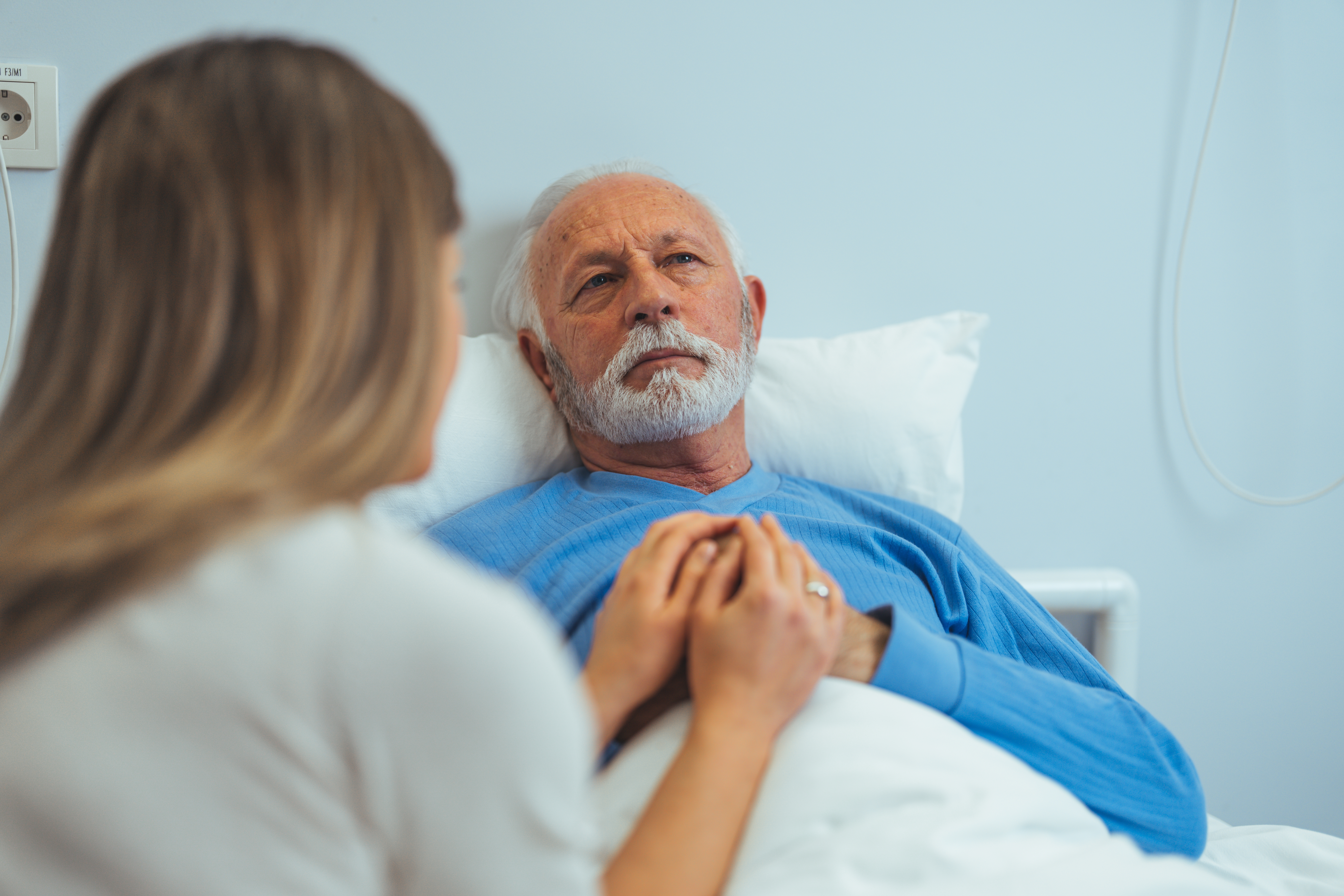 Una mujer visita a un paciente anciano en un hospital | Foto: Shutterstock