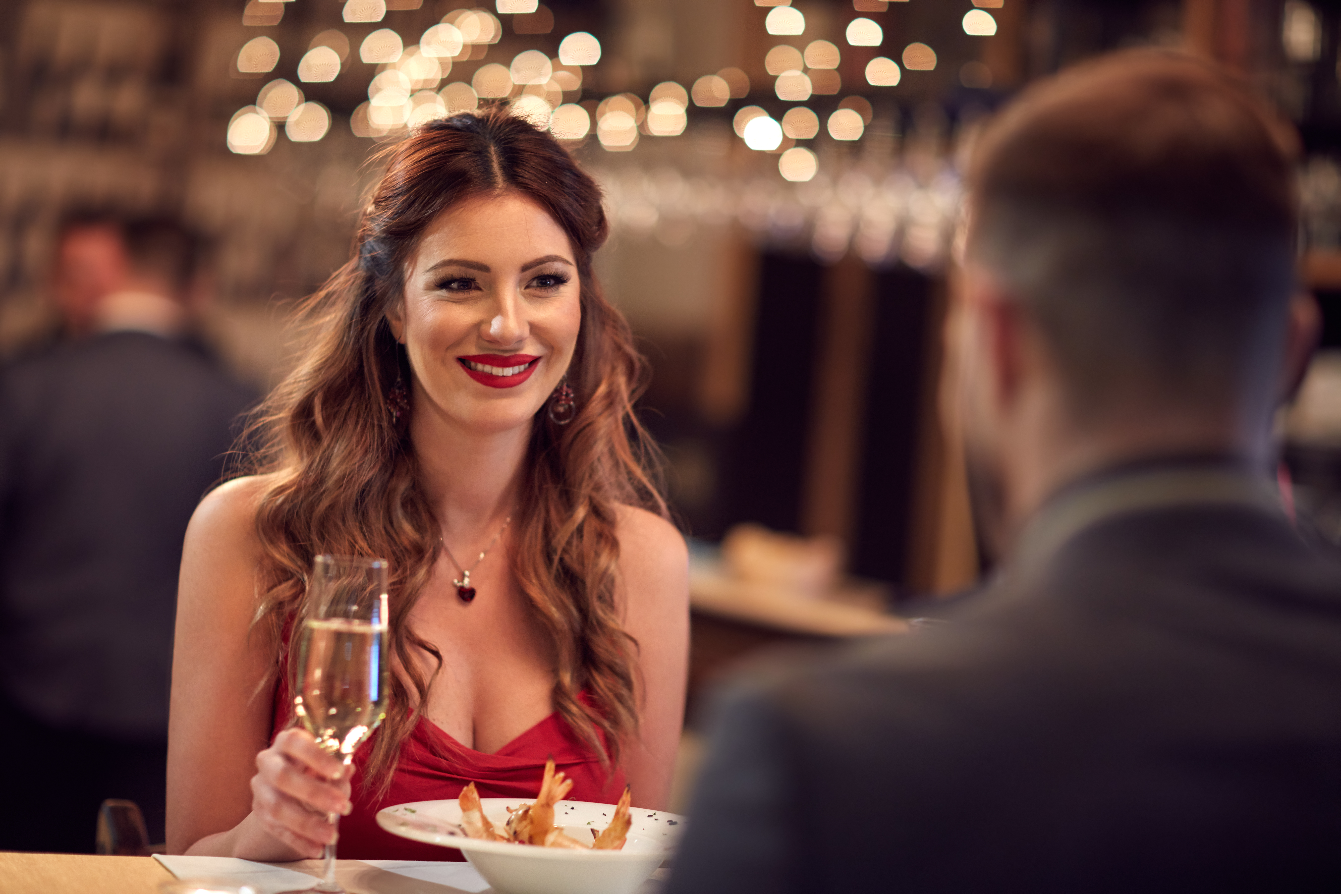 Mujer con vestido rojo cenando con su novio | Foto: Shutterstock