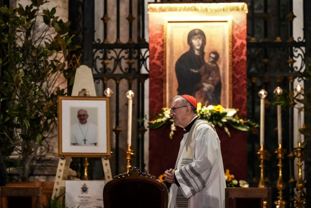 El cardenal Pietro Parolin, permanece junto a un retrato del difunto papa Francisco durante un rezo del rosario en homenaje al pontífice, en la Piazza di Santa Maria Maggiore, un día después de su fallecimiento, en Roma, el 22 de abril de 2025. | Foto: Getty Images