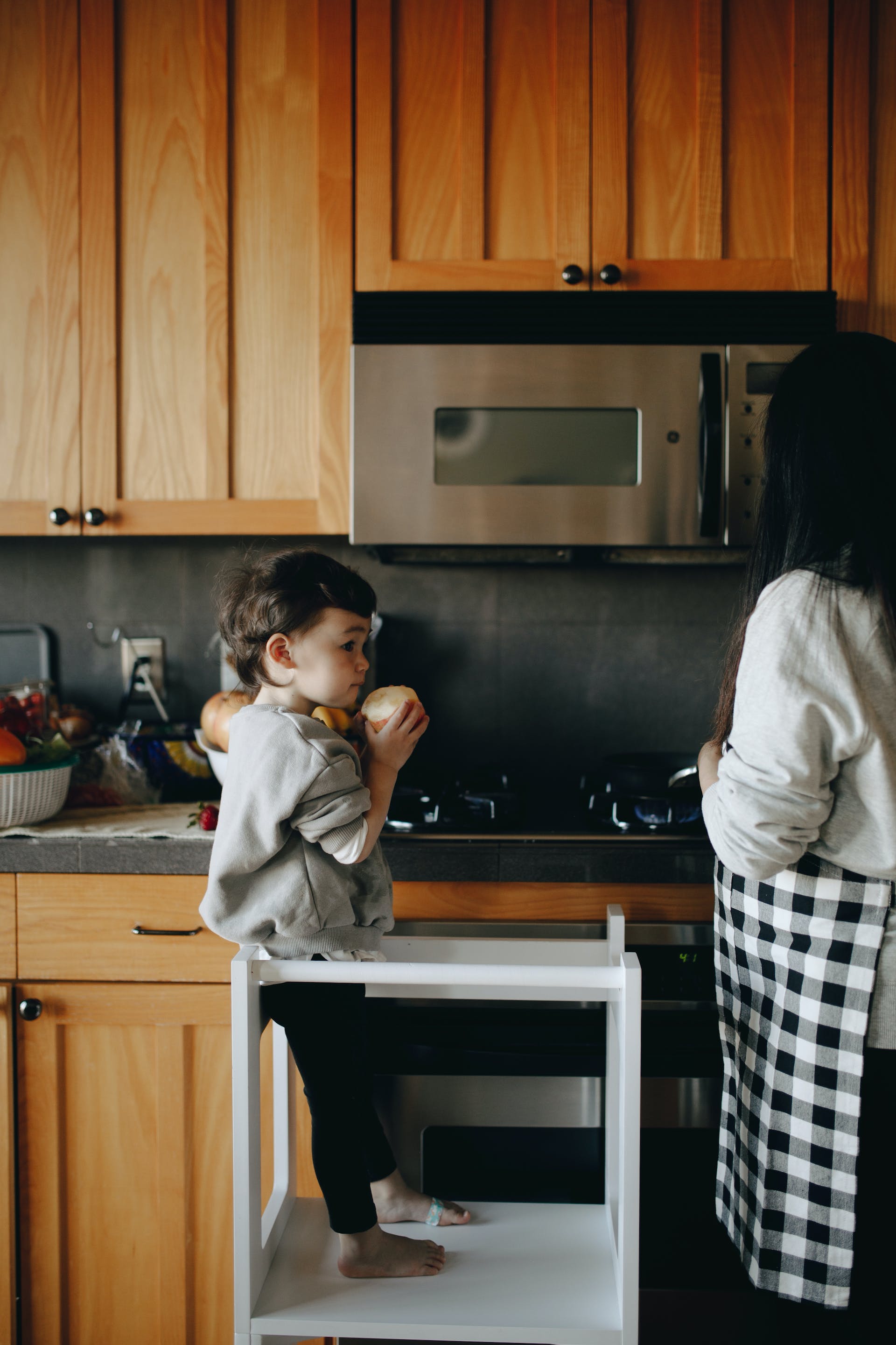 Un niño al lado de su madre en la cocina  | Foto: Pexels