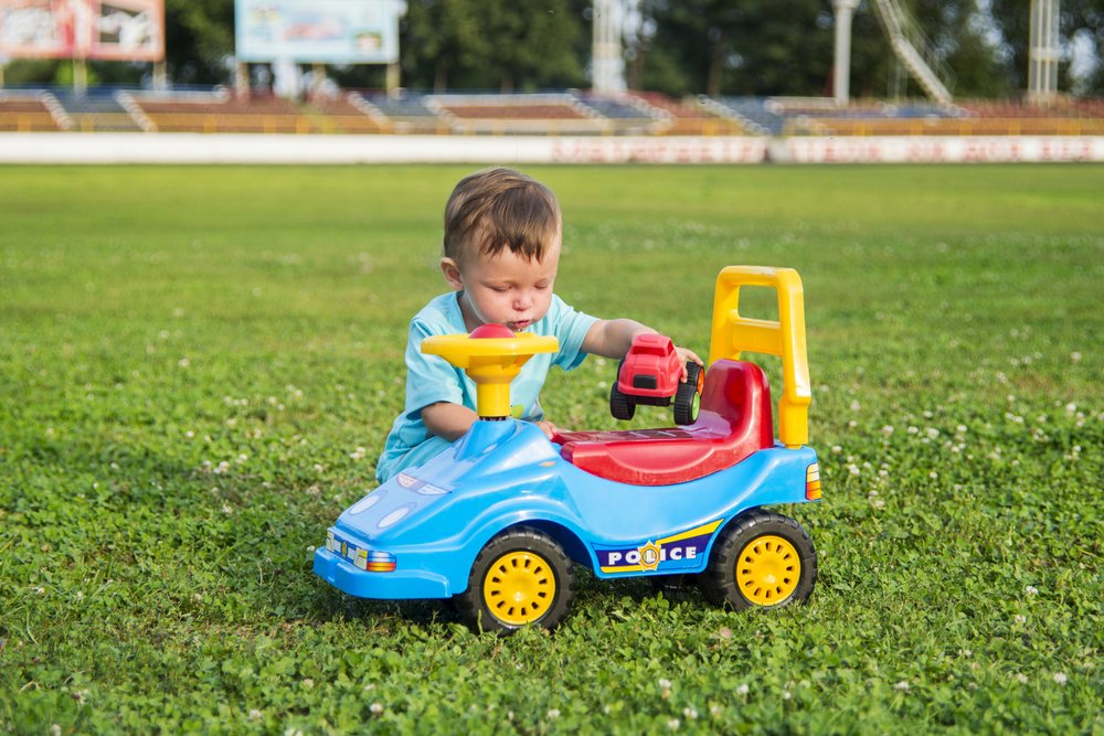 Niño jugando en el pasto con un carro de juguete. | Foto: Shutterstock