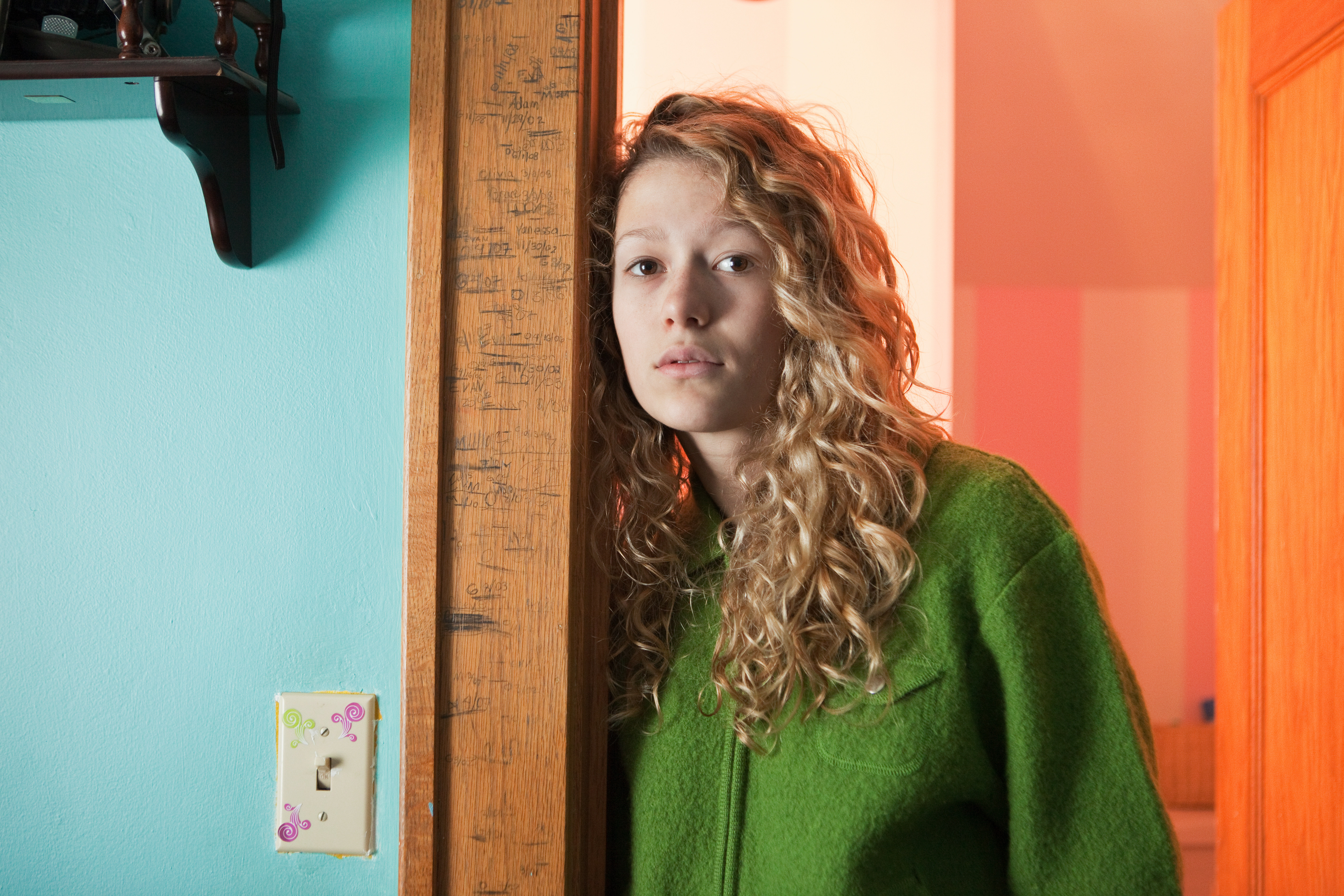 Chica adolescente apoyada en la puerta, retrato | Fuente: Getty Images