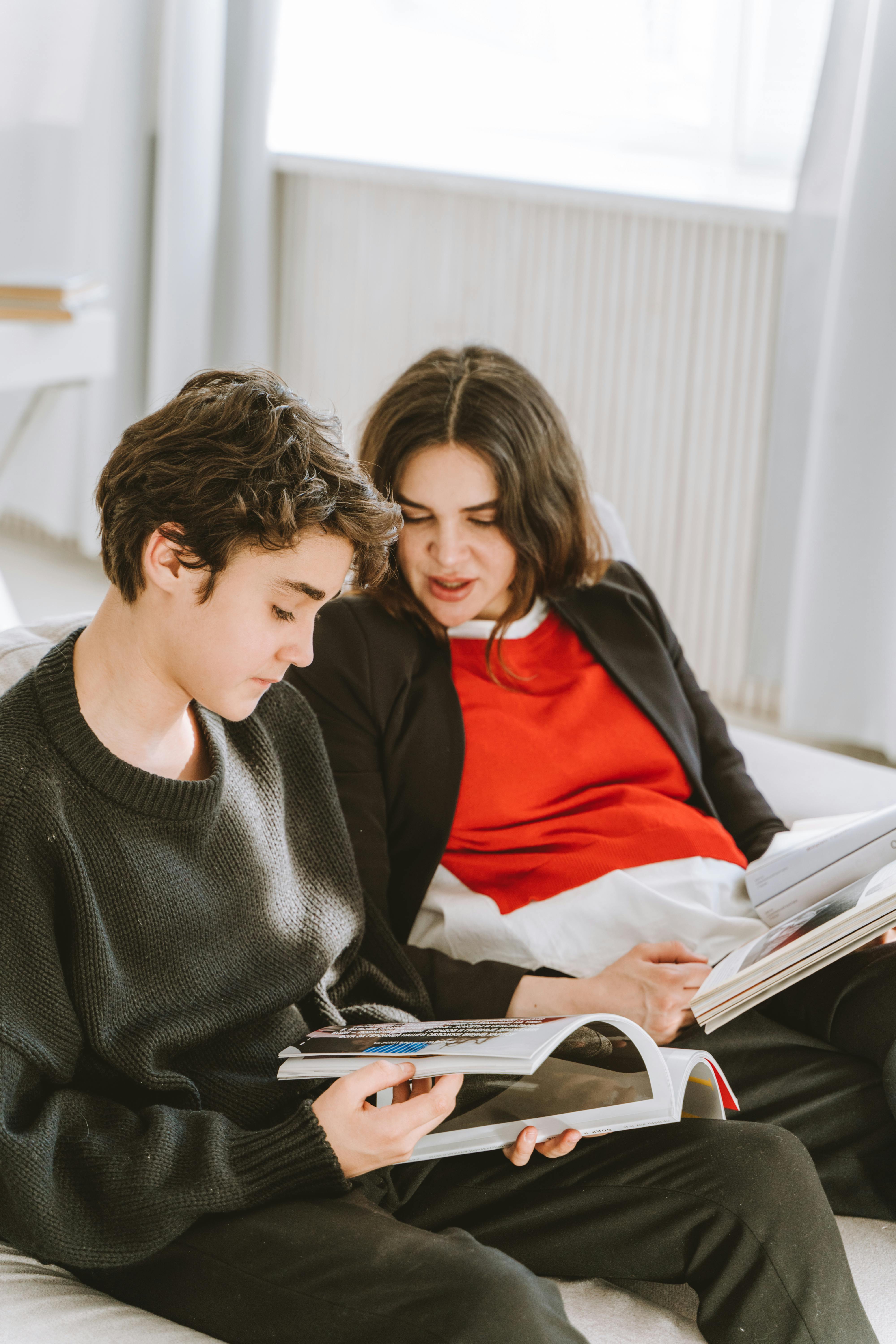 Una mujer y su hijo sentados en un sofá y mirando revistas | Fuente: Pexels