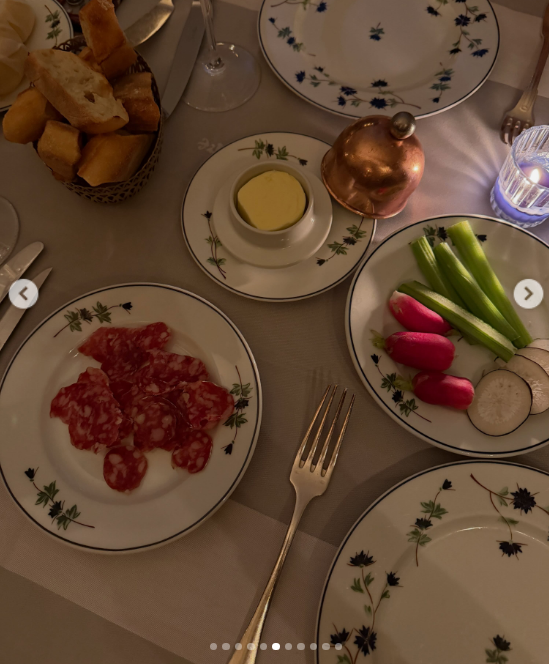 Una elegante mesa servida muestra una clásica entrada compuesta por embutidos en rodajas, manteca fresca, rabanitos enteros y bastones de apio crujiente servidos en fina vajilla decorada con detalles florales. | Fuente: Instagram/juliana.awada