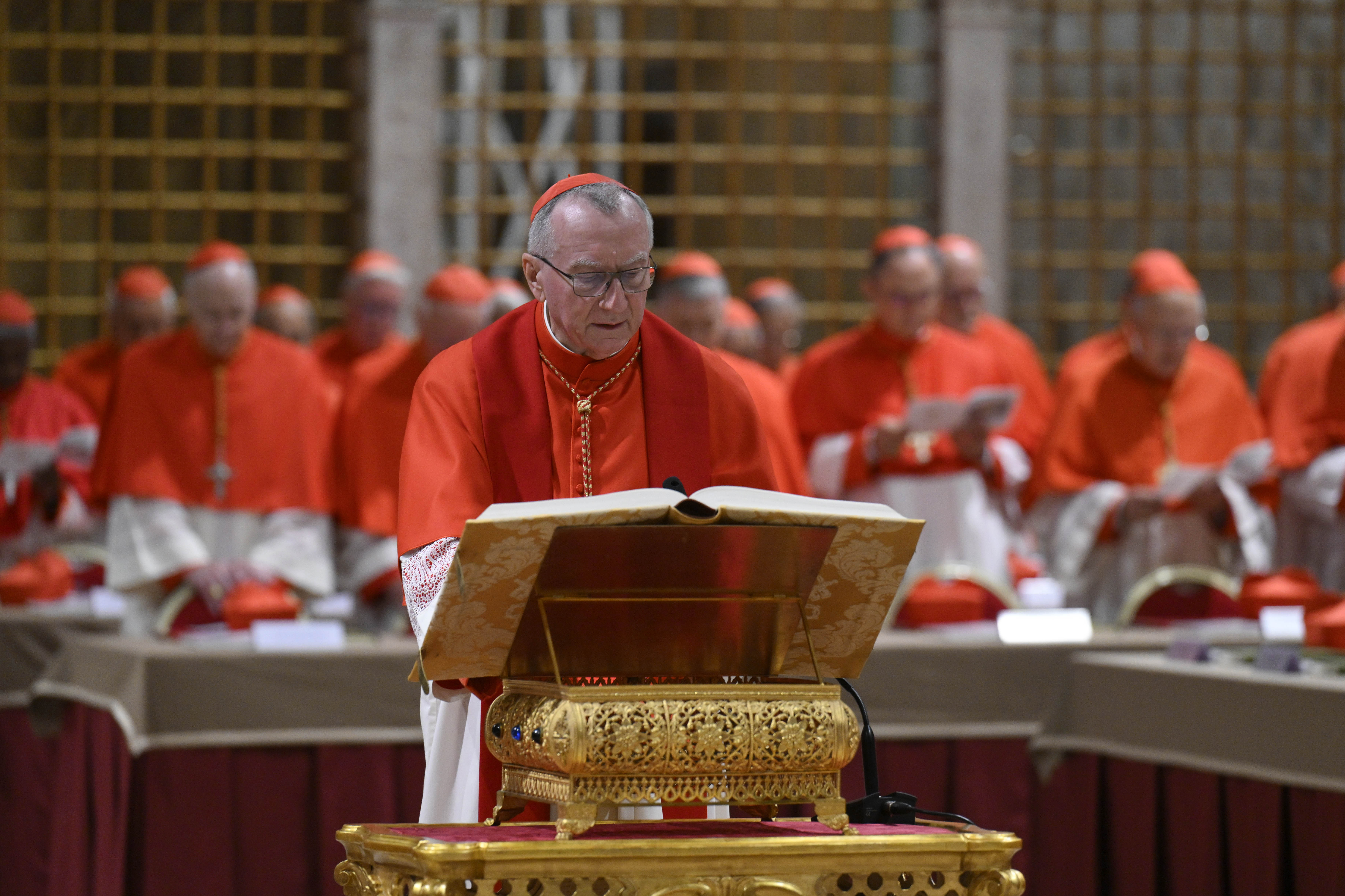 Un cardenal lee el Evangelio mientras otros rezan de pie durante el cónclave papal en el Vaticano el 7 de mayo de 2025 | Fuente: Getty Images
