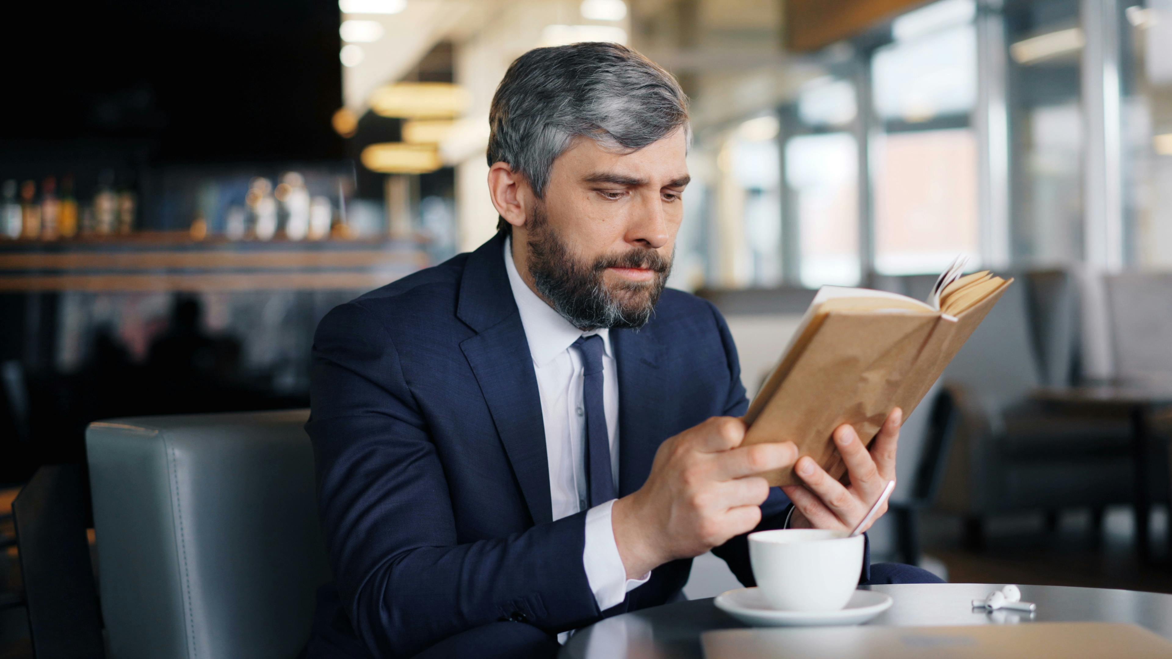 Un hombre con un libro en una cafetería | Fuente: Pexels