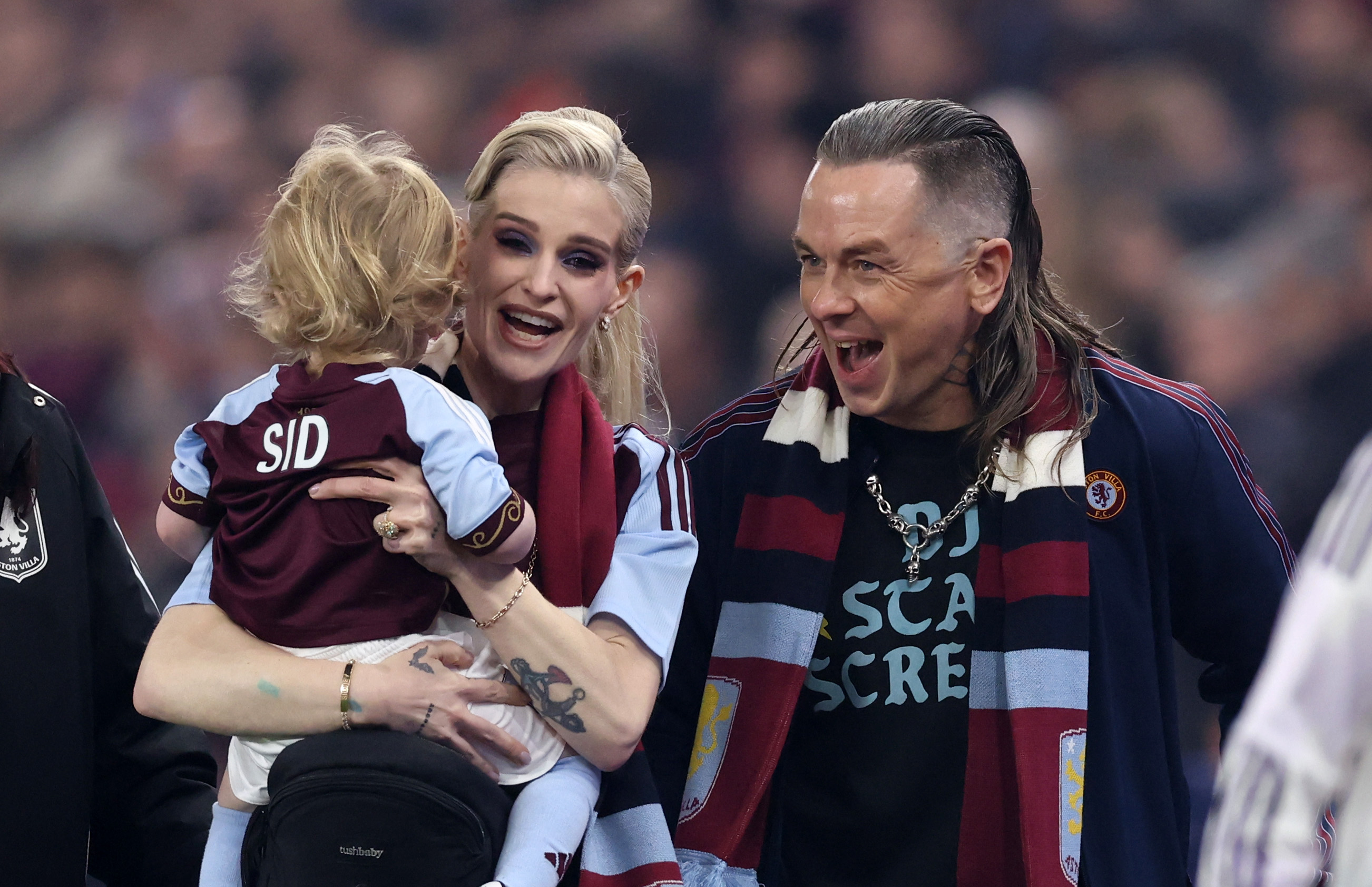 Kelly Osbourne sonreía mientras sostenía a su hijo Sidney, que llevaba una camiseta personalizada del Aston Villa, mientras Sid Wilson estaba a su lado durante una salida familiar a un partido de fútbol en diciembre de 2025. | Fuente: Getty Images