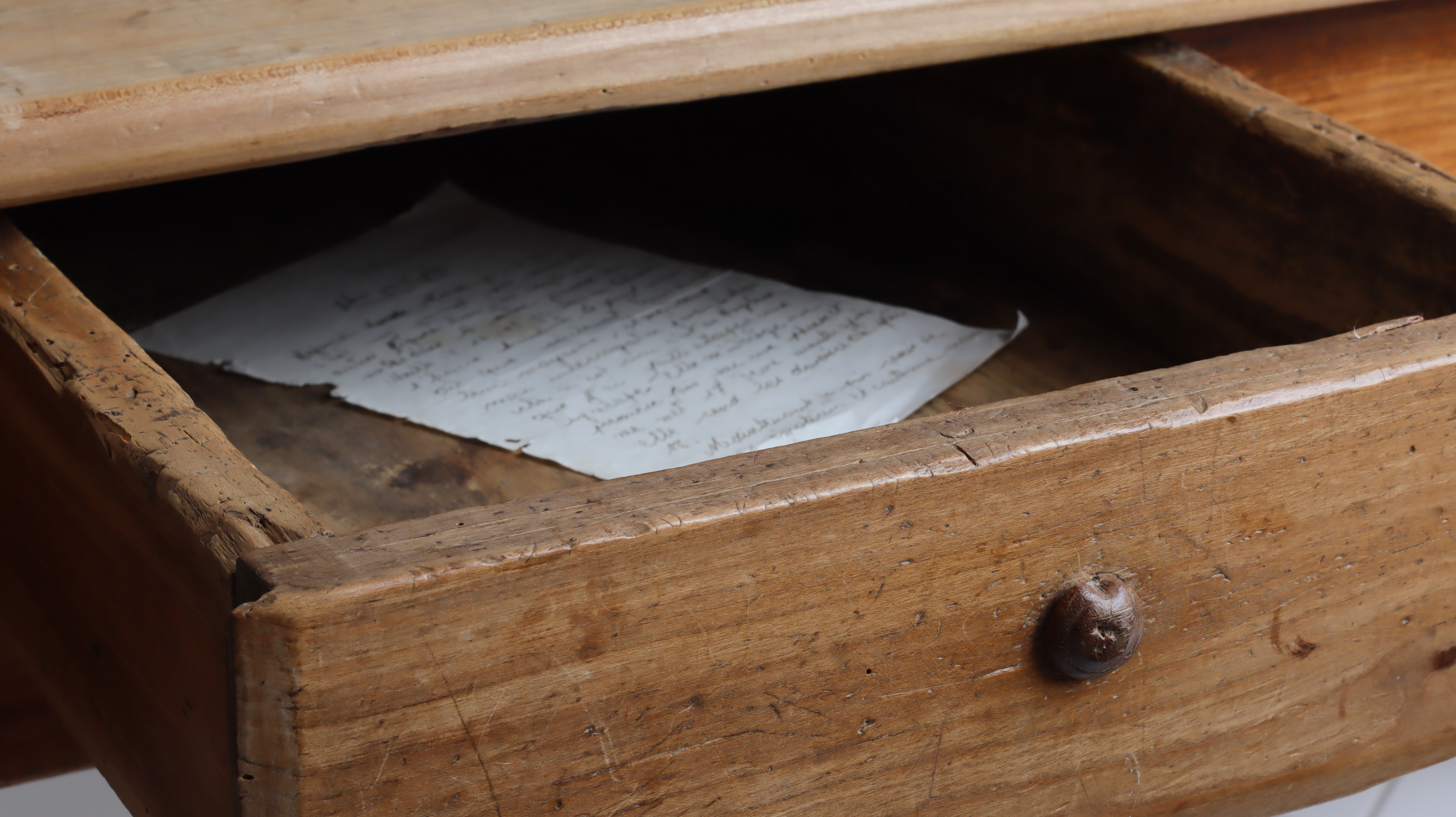 Cajón medio abierto de una vieja mesa de madera vintage con una vieja carta manuscrita en su interior | Foto: Shutterstock