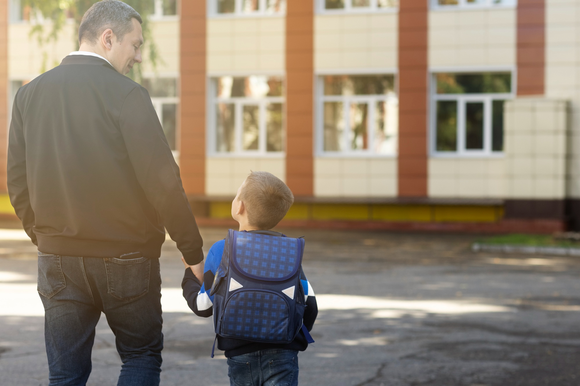 Un niño con una mochila mirando a su padre | Fuente: Freepik