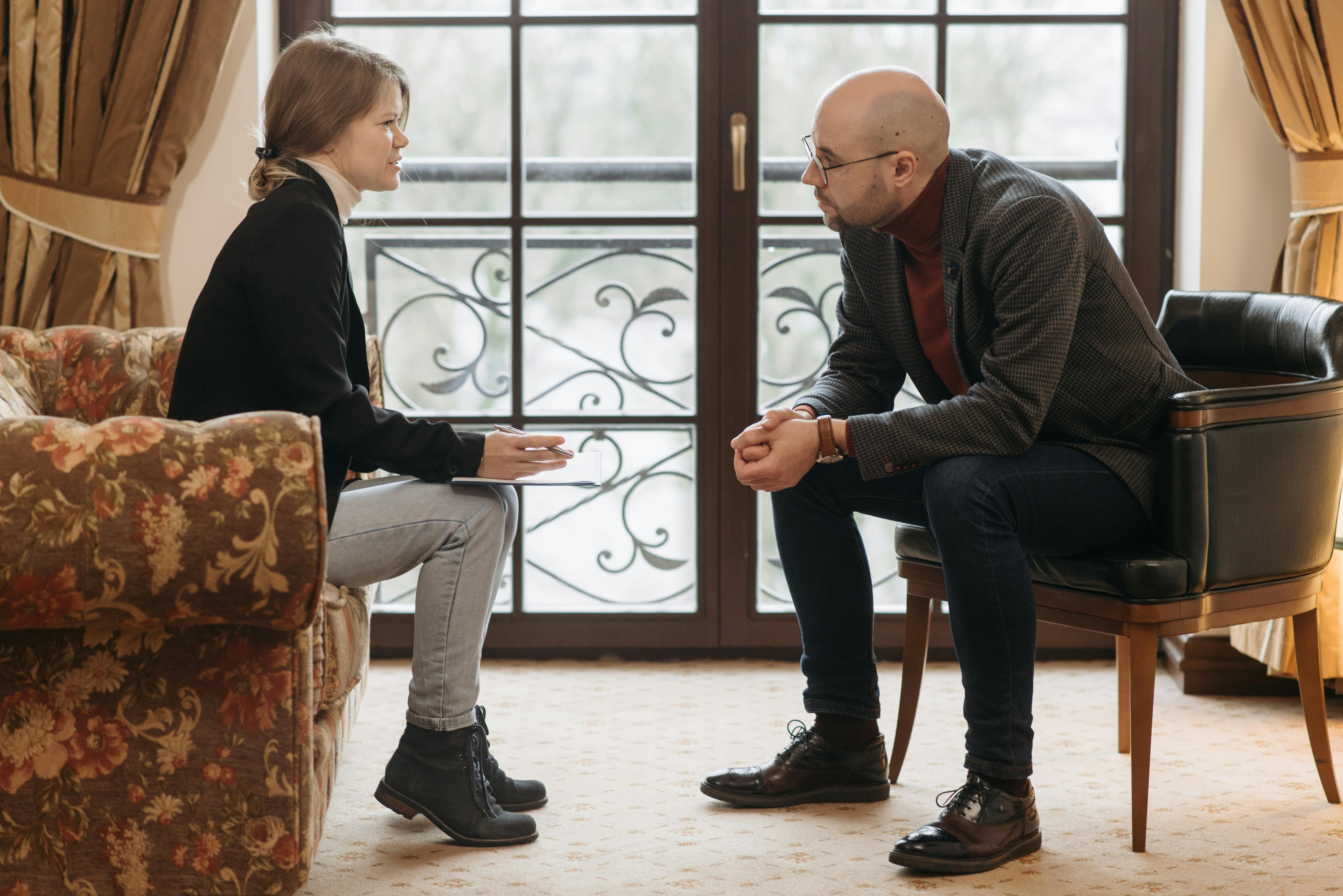 Hombre inclinado cerca de una mujer mientras le habla | Fuente: Pexels