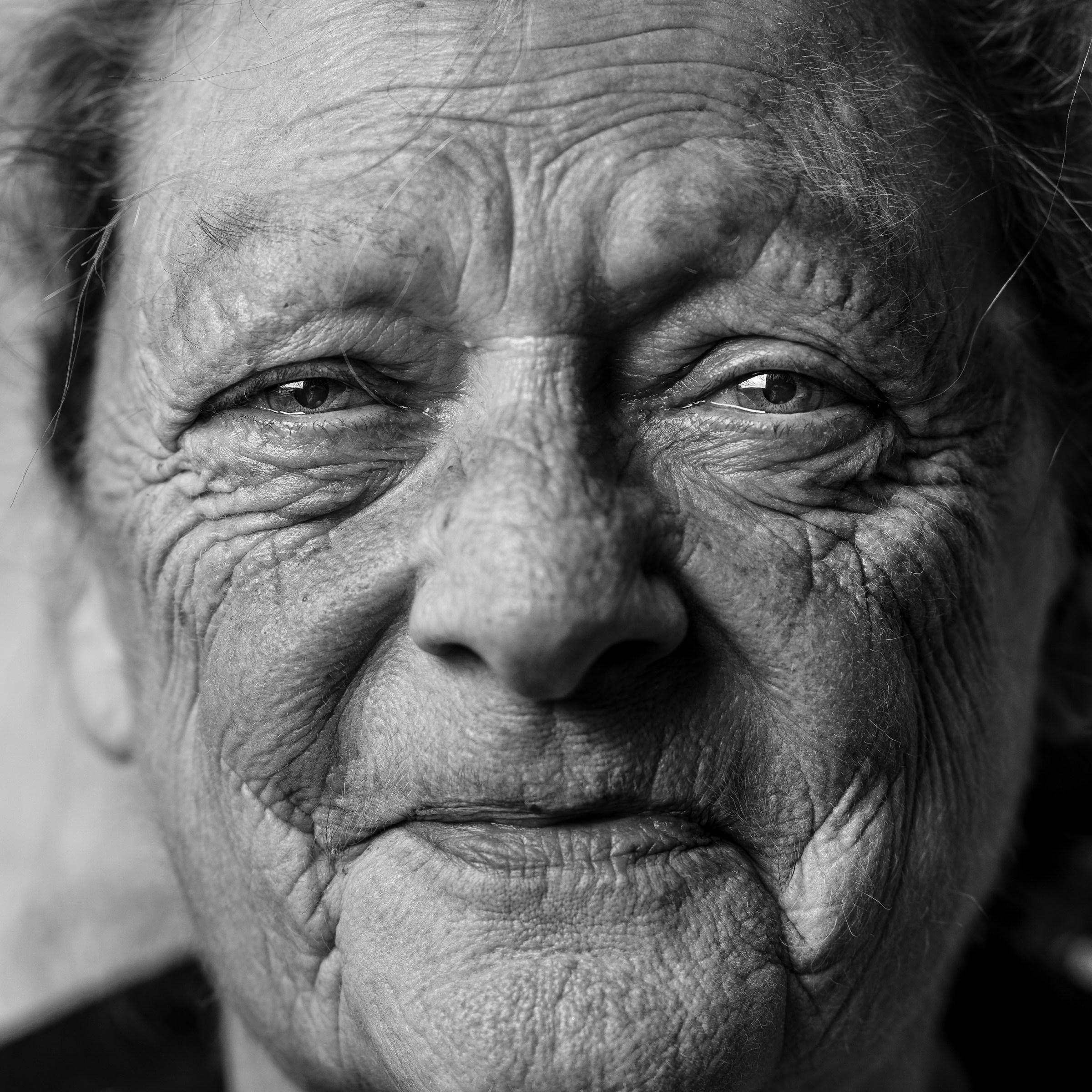 Foto en escala de grises de una mujer mayor sonriente | Fuente: Unsplash