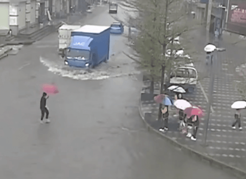 Maestra cargando a sus alumnos sobre una calle inundada en China. | Imagen: YouTube/Daily Mail 