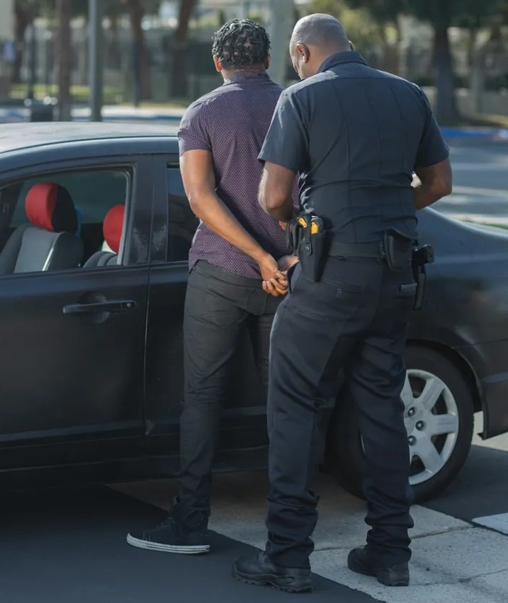 Un policía y un hombre esposado contra un vehículo. | Foto: Pexels