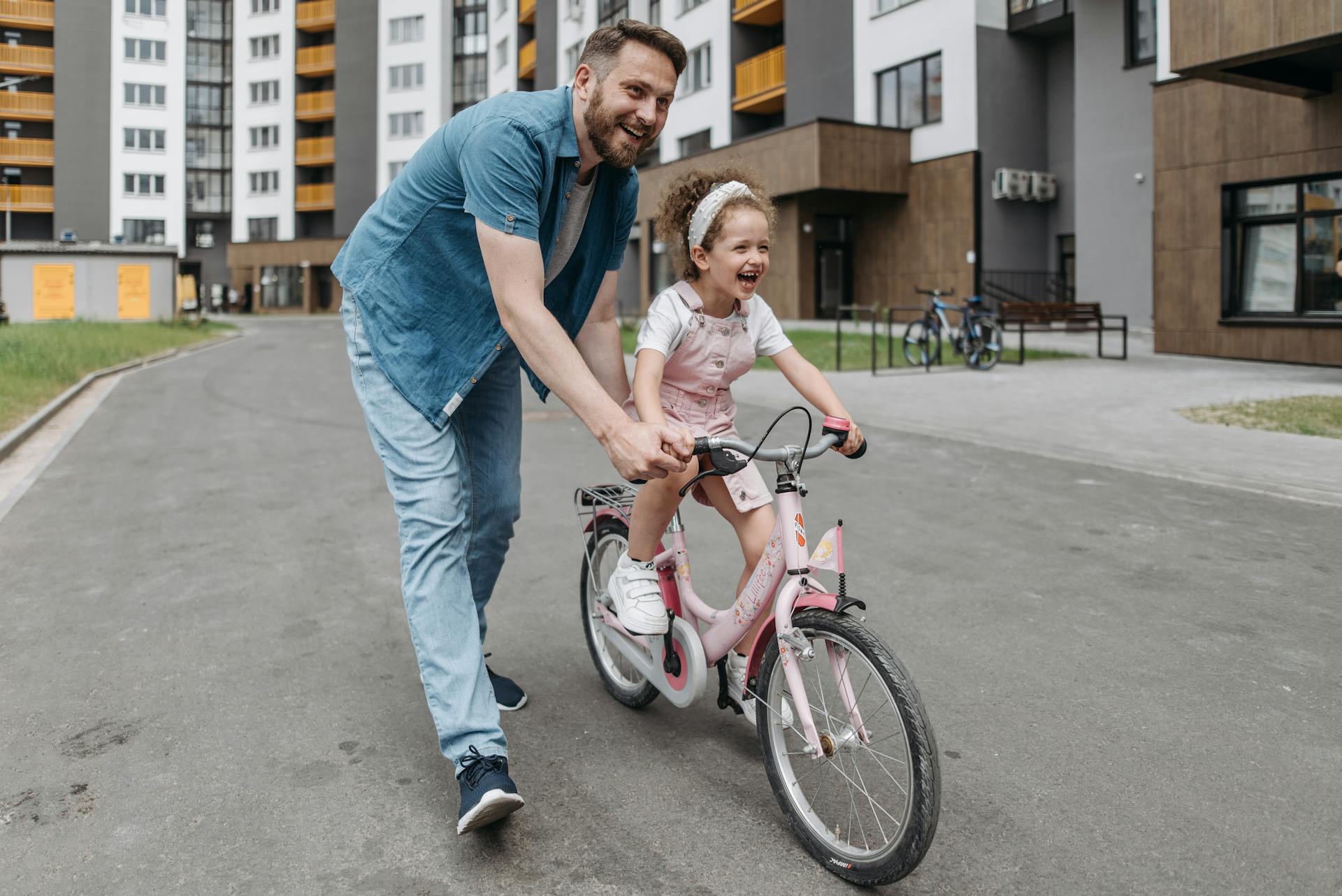 Un hombre ayudando a su hija a montar en bici | Fuente: Pexels
