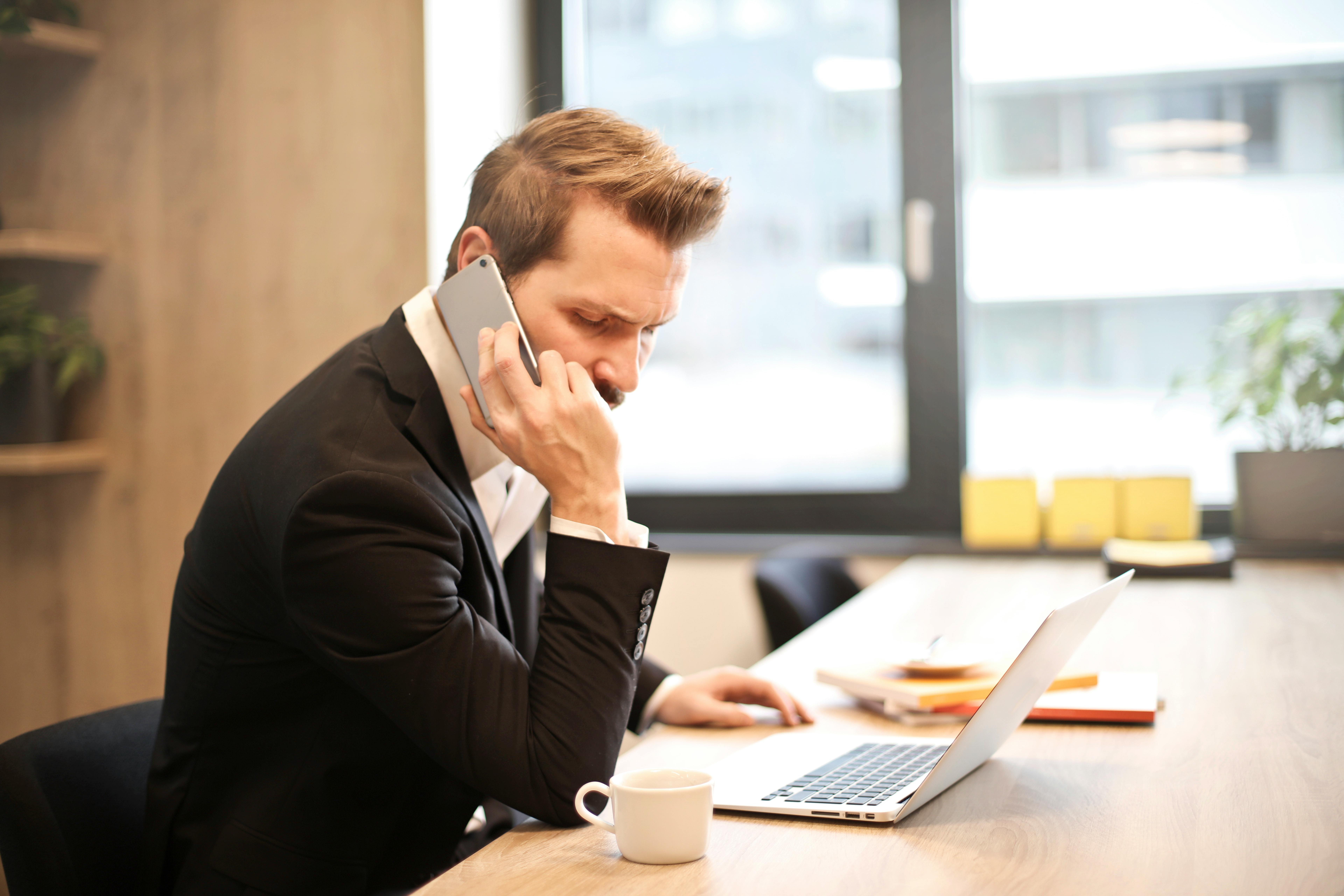 Hombre habla por teléfono en su despacho | Fuente: Pexels