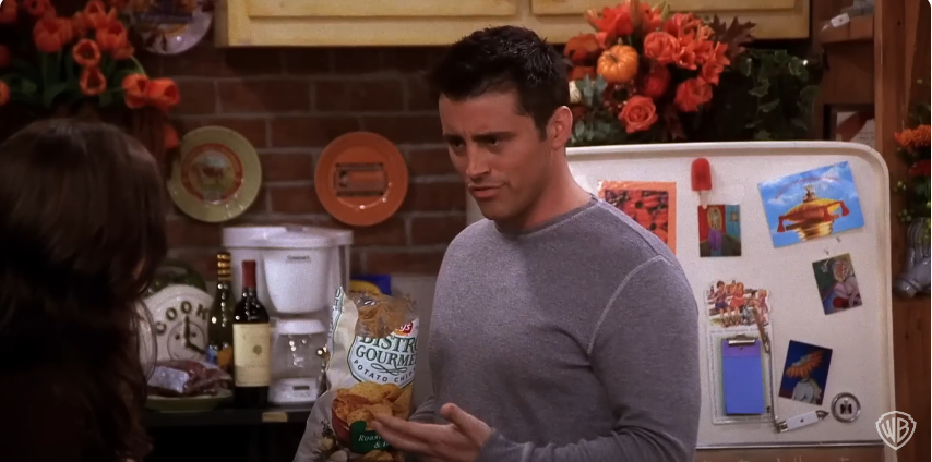 Matt Leblanc como Joey sosteniendo un paquete de patatas fritas en el plató de "Friends". Fuente: YouTube/@warnerbrostv