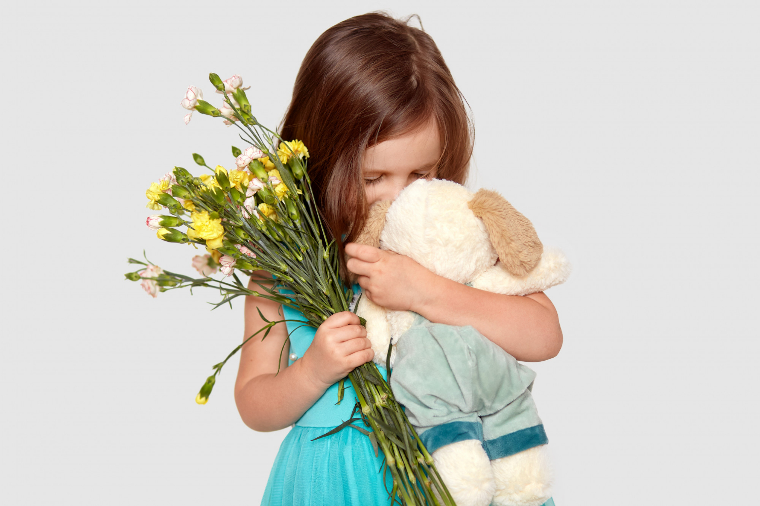 Una niña triste con su peluche y flores en la mano | Fuente: Freepik