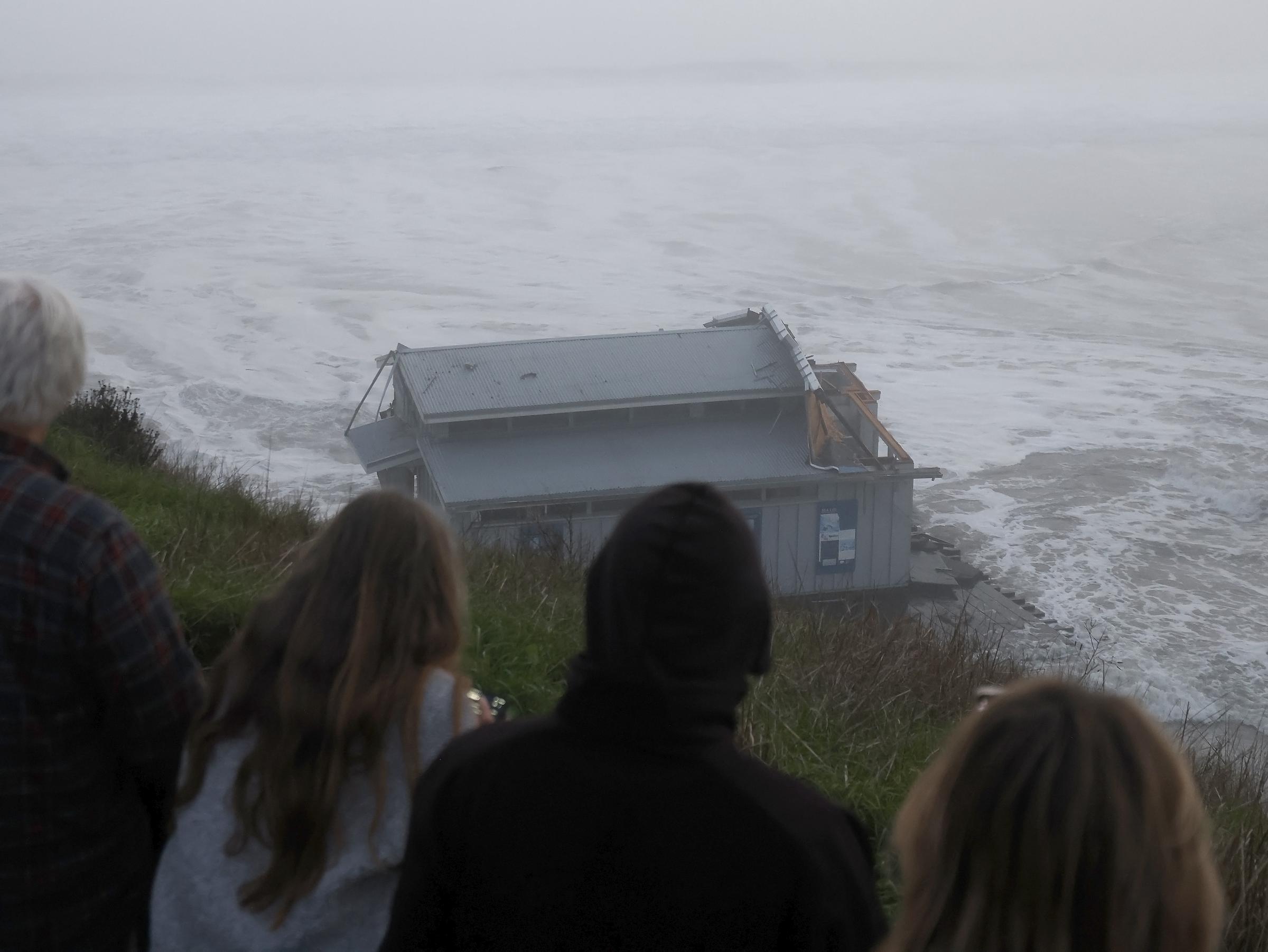 Un grupo de personas observa el muelle derrumbado en el embarcadero de Santa Cruz, California, el 23 de diciembre de 2024 | Fuente: Getty Images