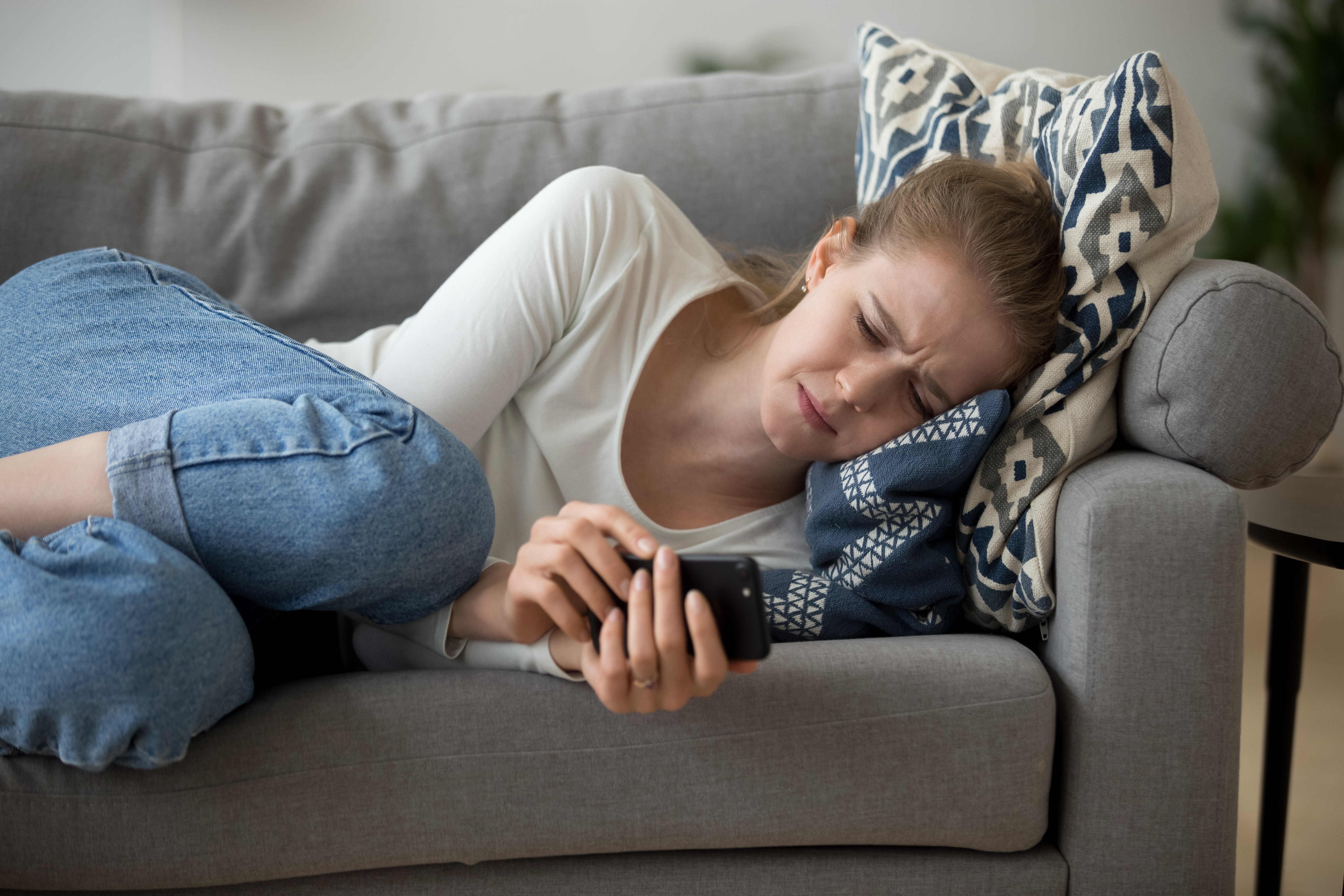 Una joven llorando recostada en un sofá | Fuente: Shutterstock