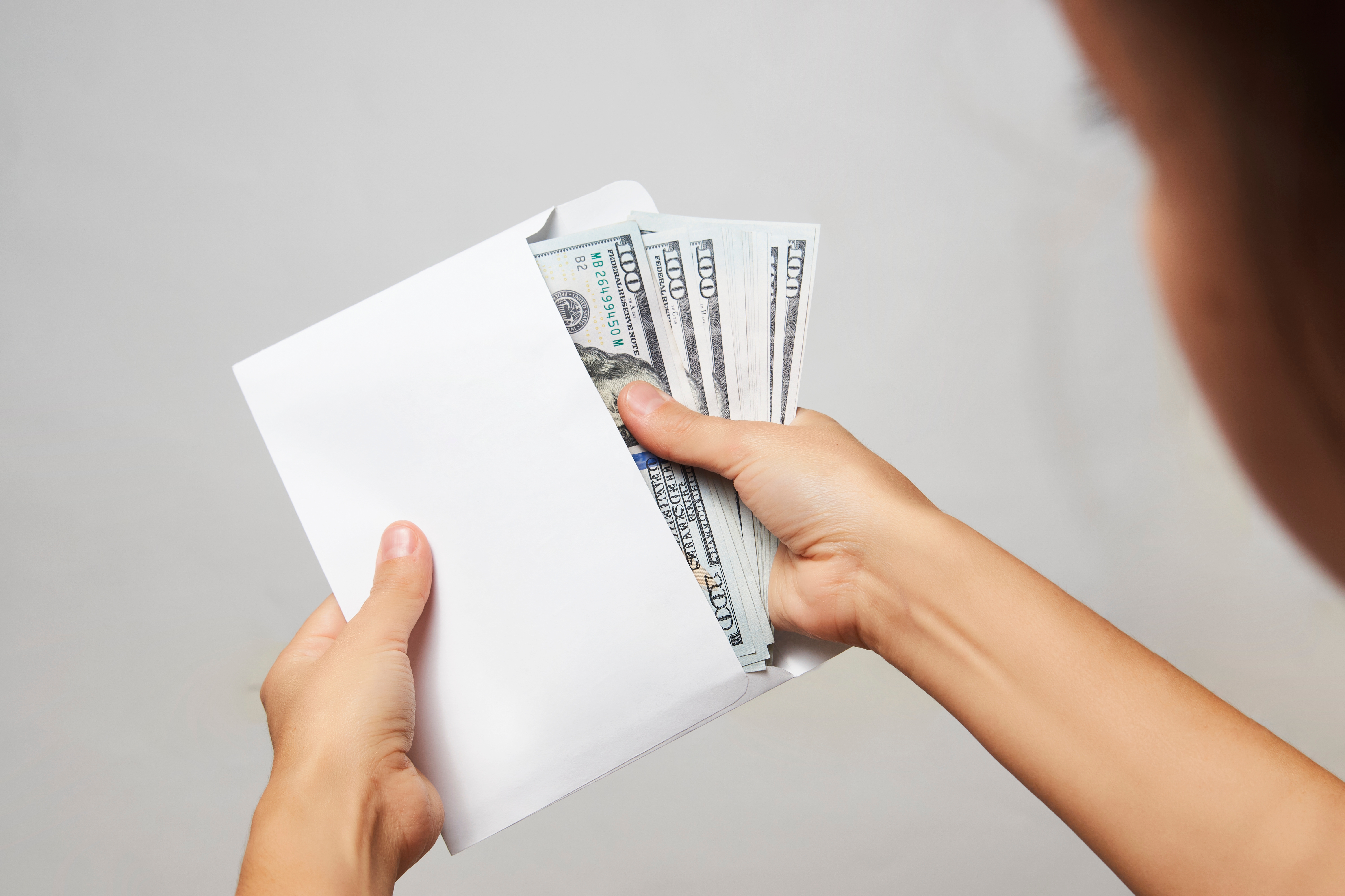 Mujer saca el dinero del sobre | Fuente: Shutterstock.com