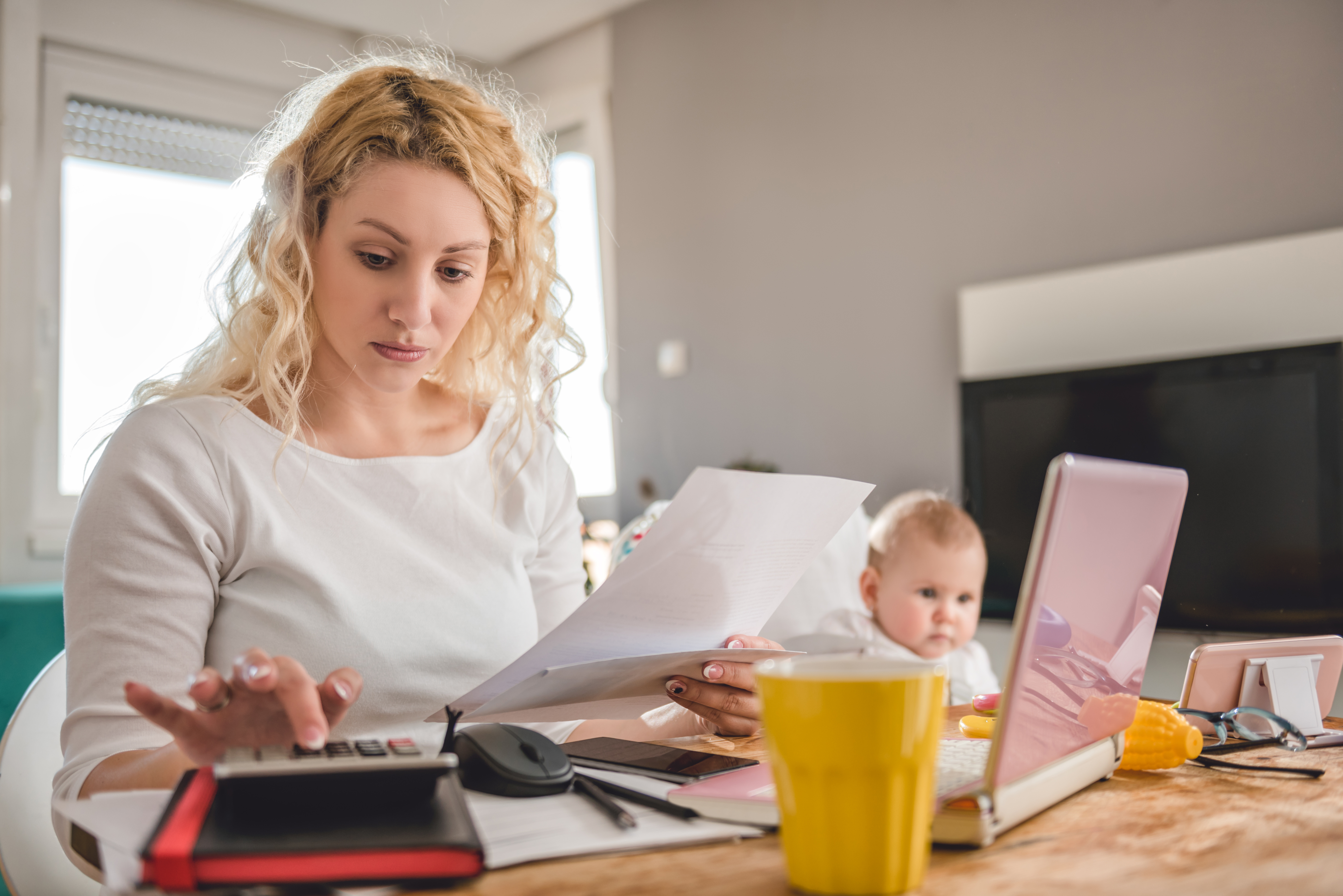 Una mujer con un niño sostiene un papel mientras calcula | Fuente: Shutterstock