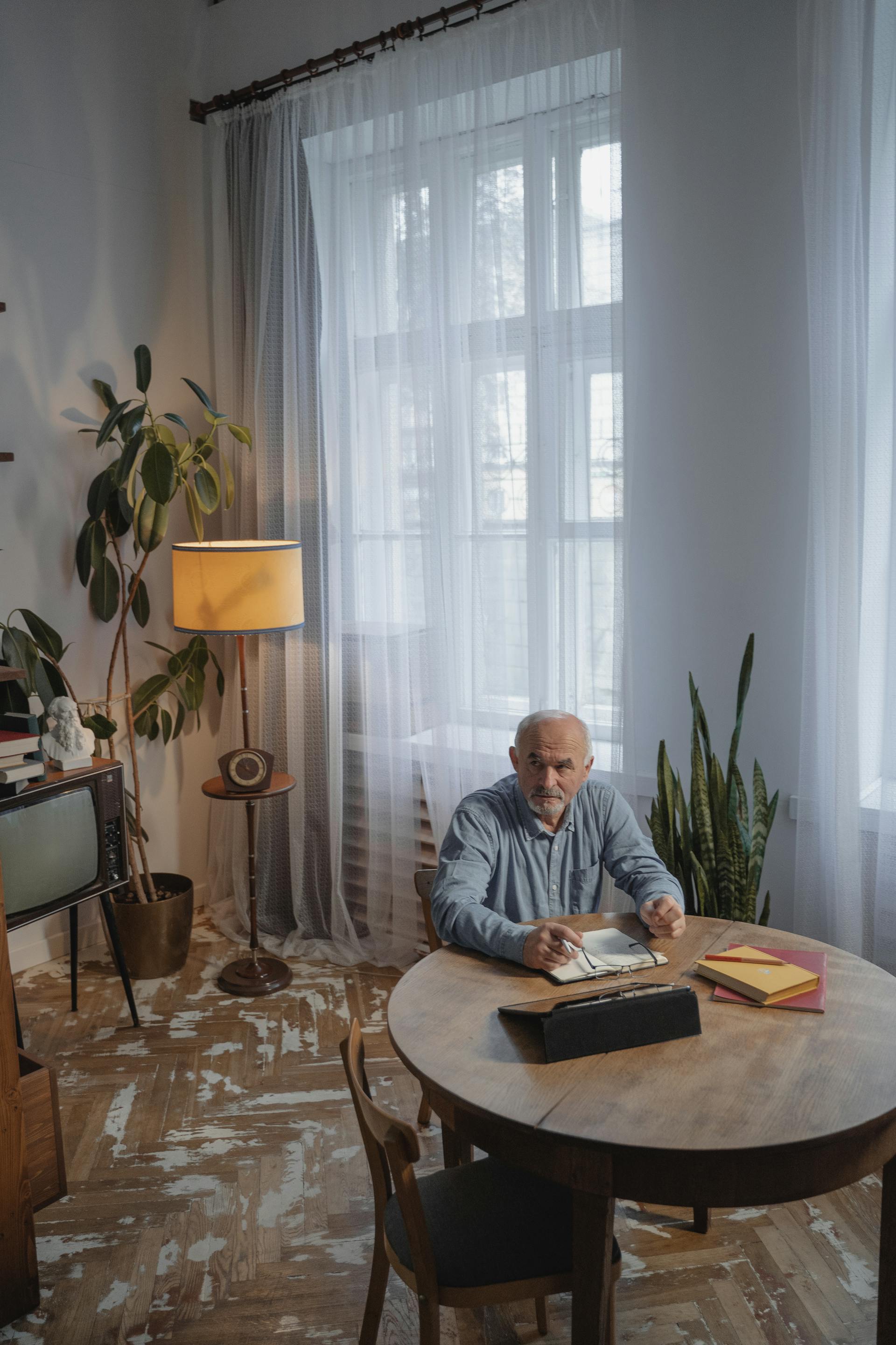 Un hombre mayor sentado en una silla de madera marrón mirando hacia arriba | Fuente: Pexels