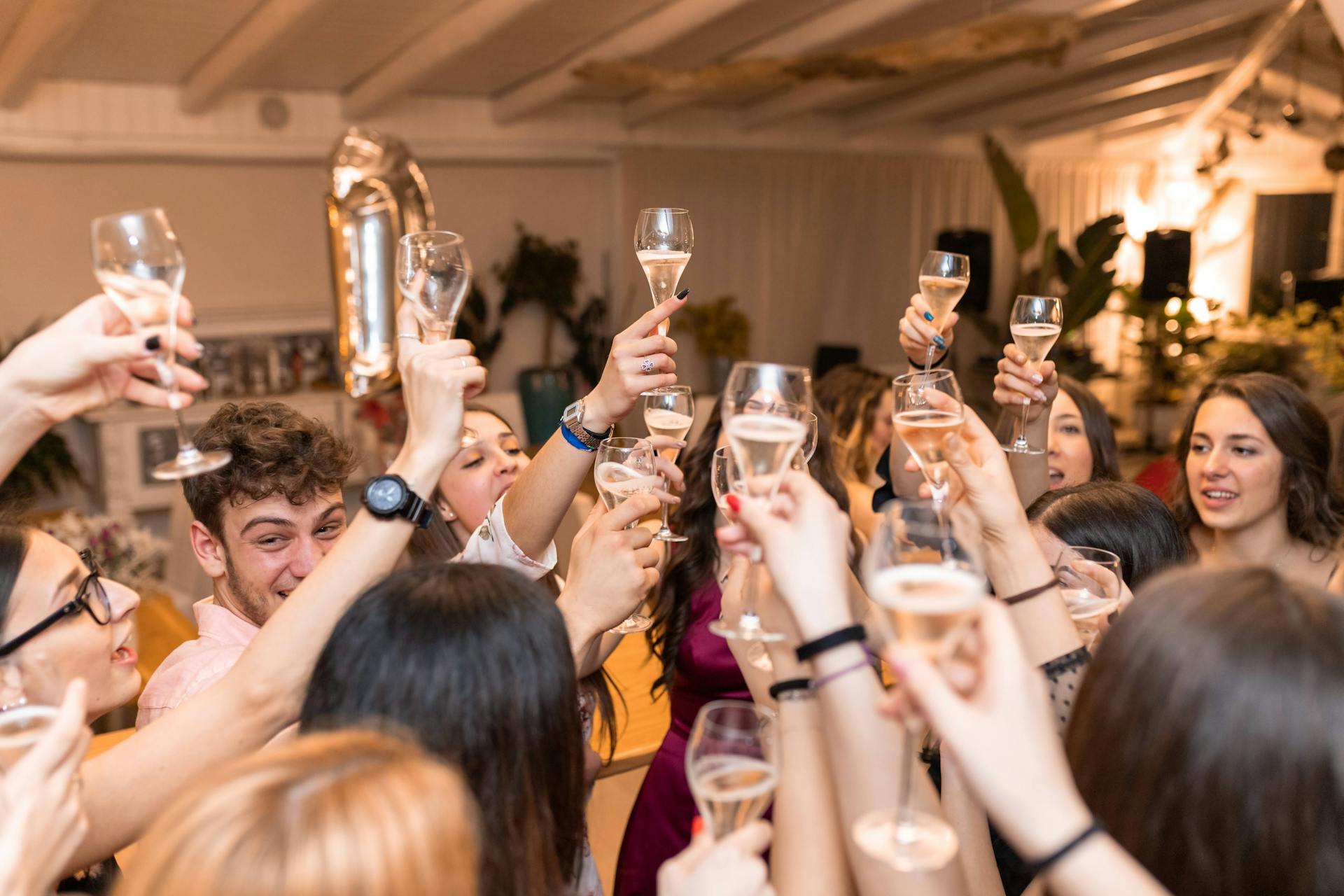 Hombres y mujeres jóvenes levantando sus copas de bebida en un restaurante | Fuente: Pexels