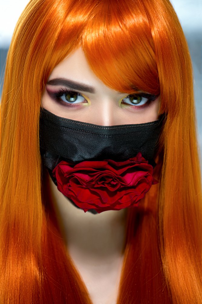 Mujer pelirroja usando tapaboca negro y maquillaje de ojos resaltante. | Foto: Shutterstock