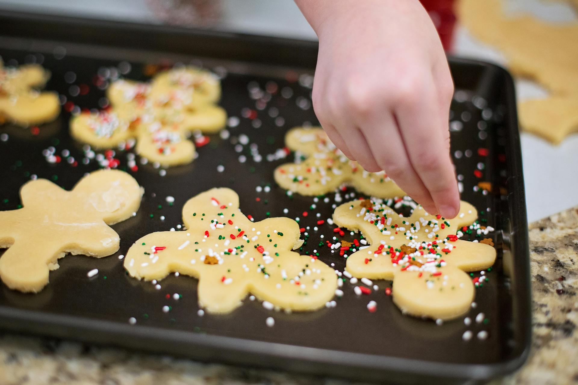 Una chica echando virutas sobre galletas de jengibre | Fuente: Pexels