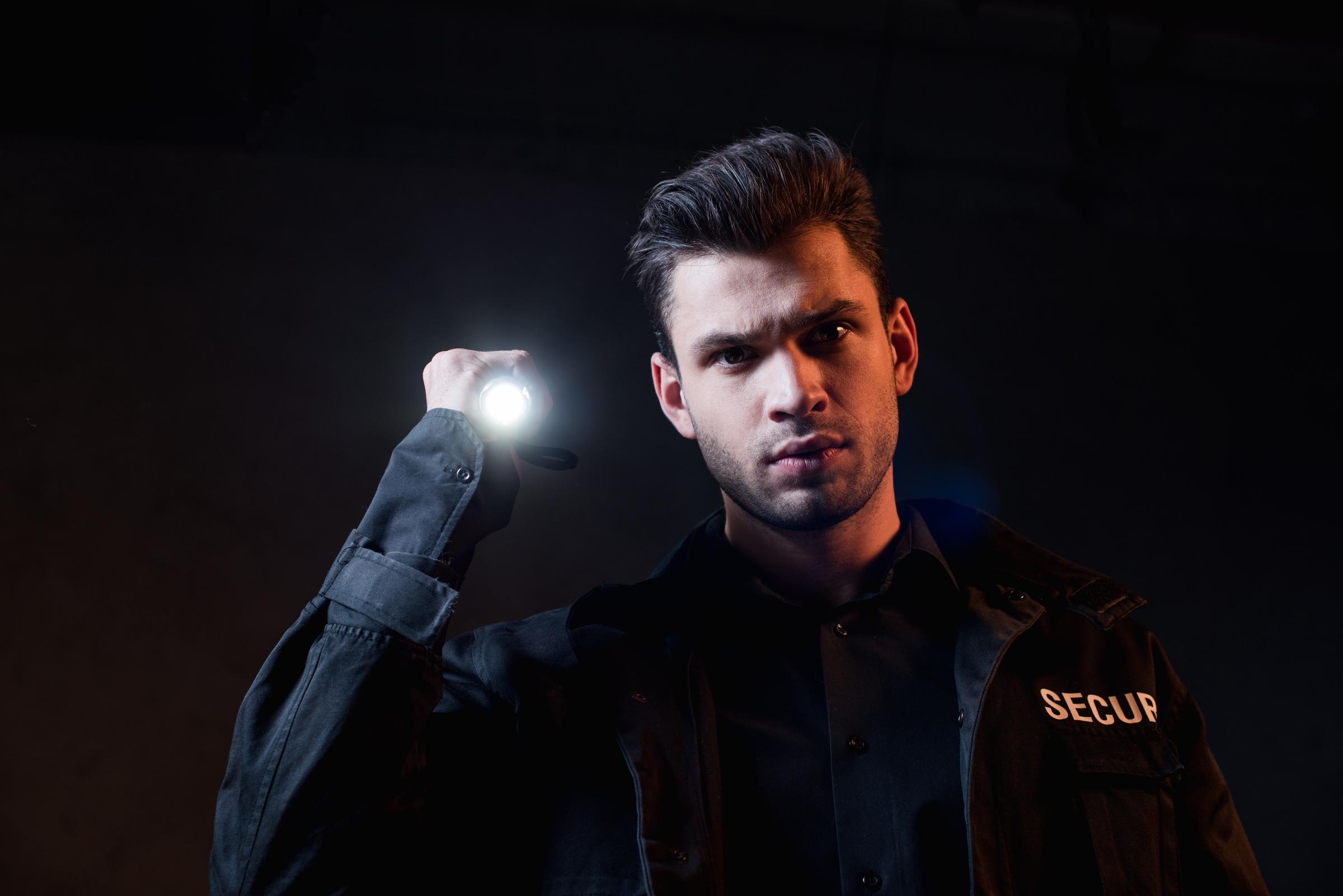 Guardia de seguridad sujetando una linterna | Fuente: Shutterstock